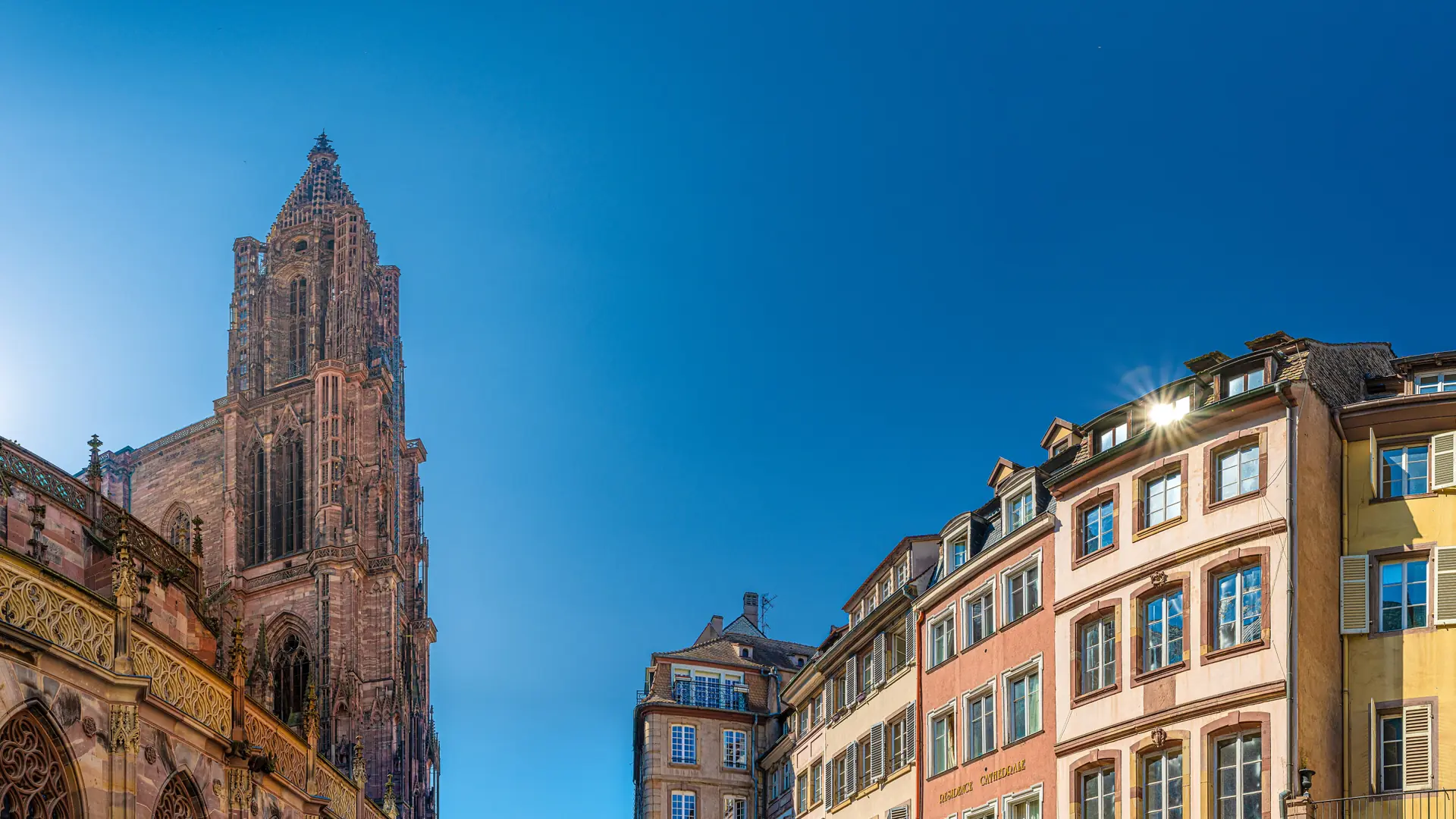 Strasbourg Cathedral tower and pink sandstone buildings beside the cathedral square