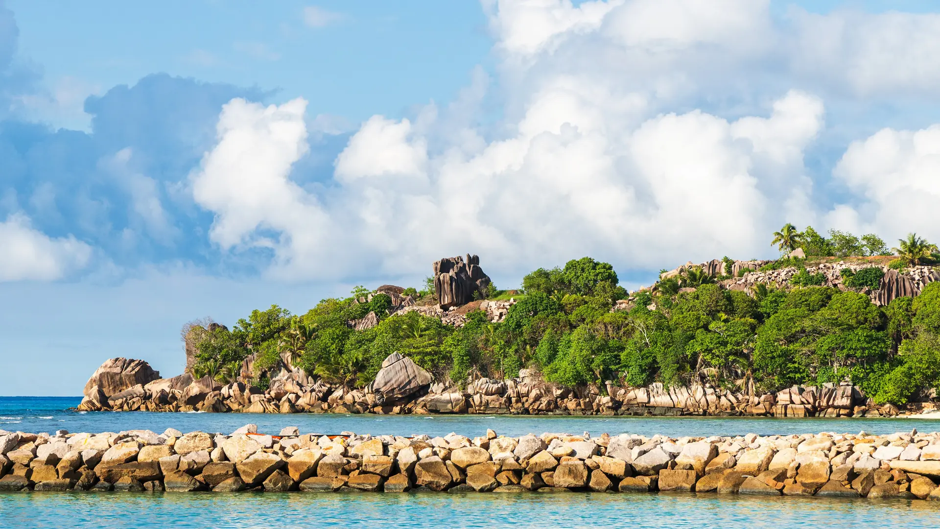 Sunlit granite coast near the ferry harbour at La Passe on La Digue
