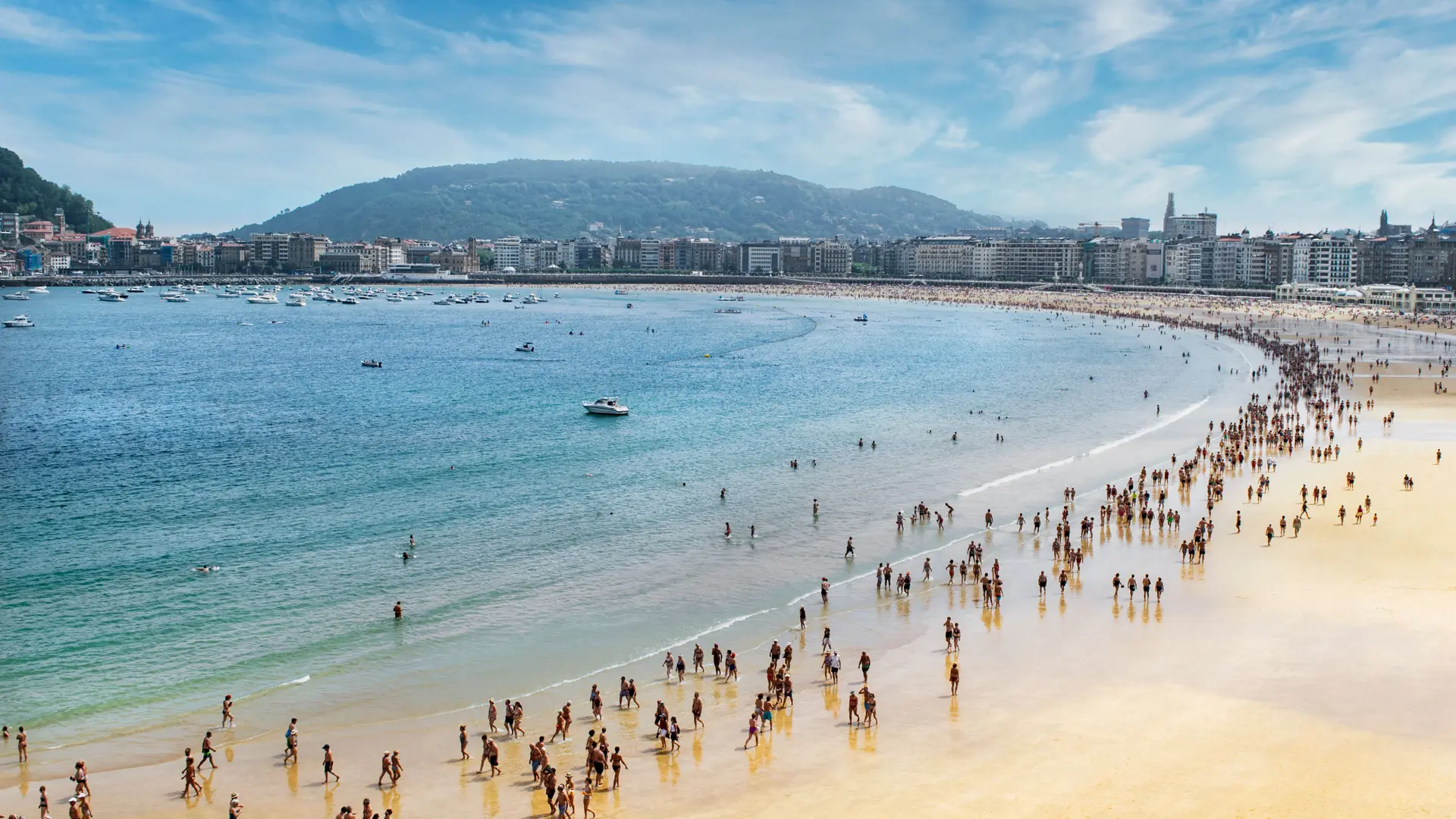 La Concha’s curving sandy beach and blue bay beside San Sebastián’s waterfront buildings.