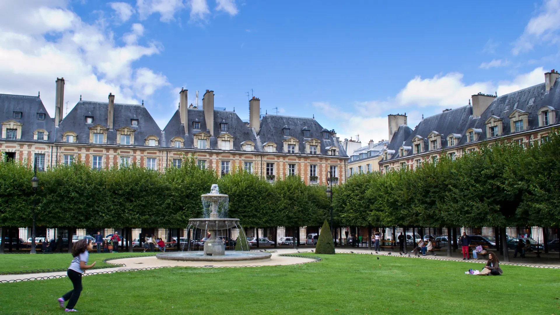 A fountain, lawns and red-brick facades in Place des Vosges, Paris