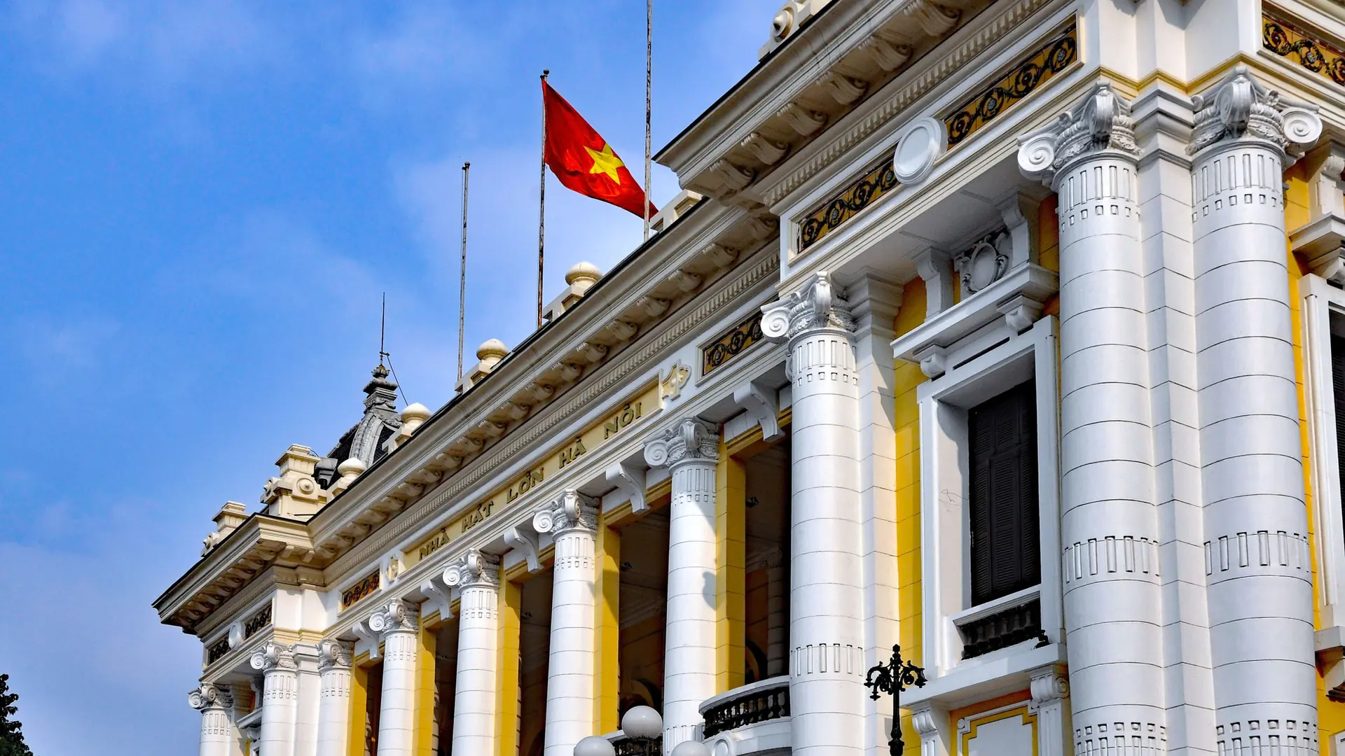 White columns and a Vietnamese flag on the facade of Hanoi Opera House.