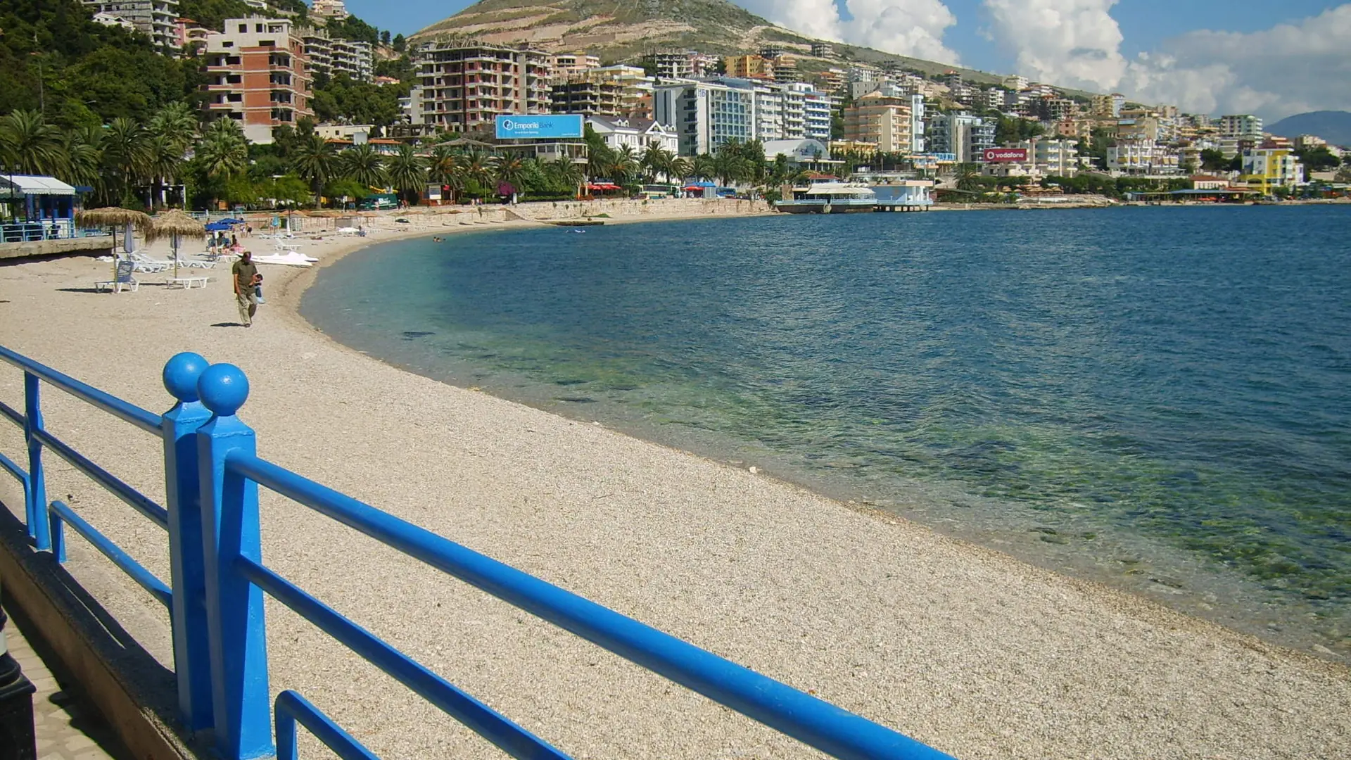 The town beach and railed promenade curving around Sarandë's bay on a sunny day