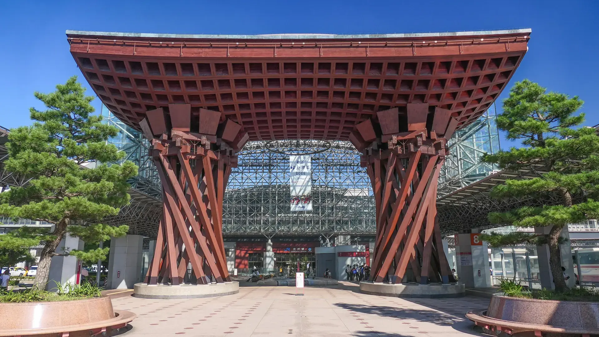 Kanazawa Station's dramatic wooden Tsuzumi-mon gate under a brilliant blue sky