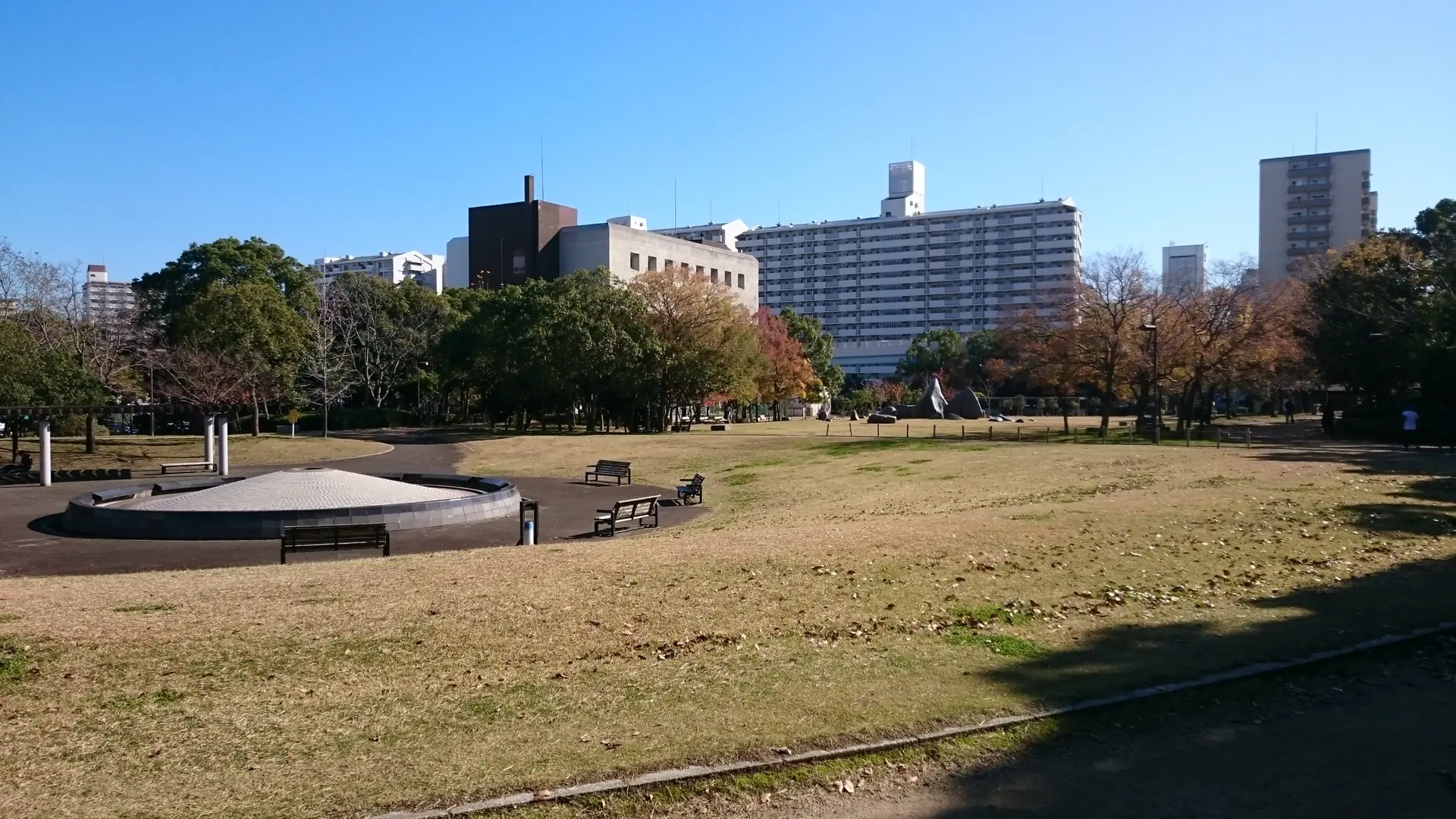 sunlit lawn and hotel buildings at Port Island's Naka Park in Kobe