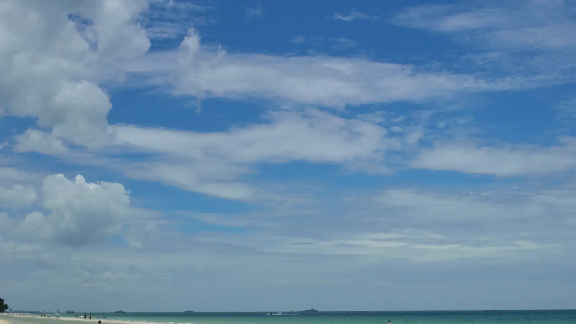 Sunlit Hua Hin shoreline beside blue Gulf of Thailand water