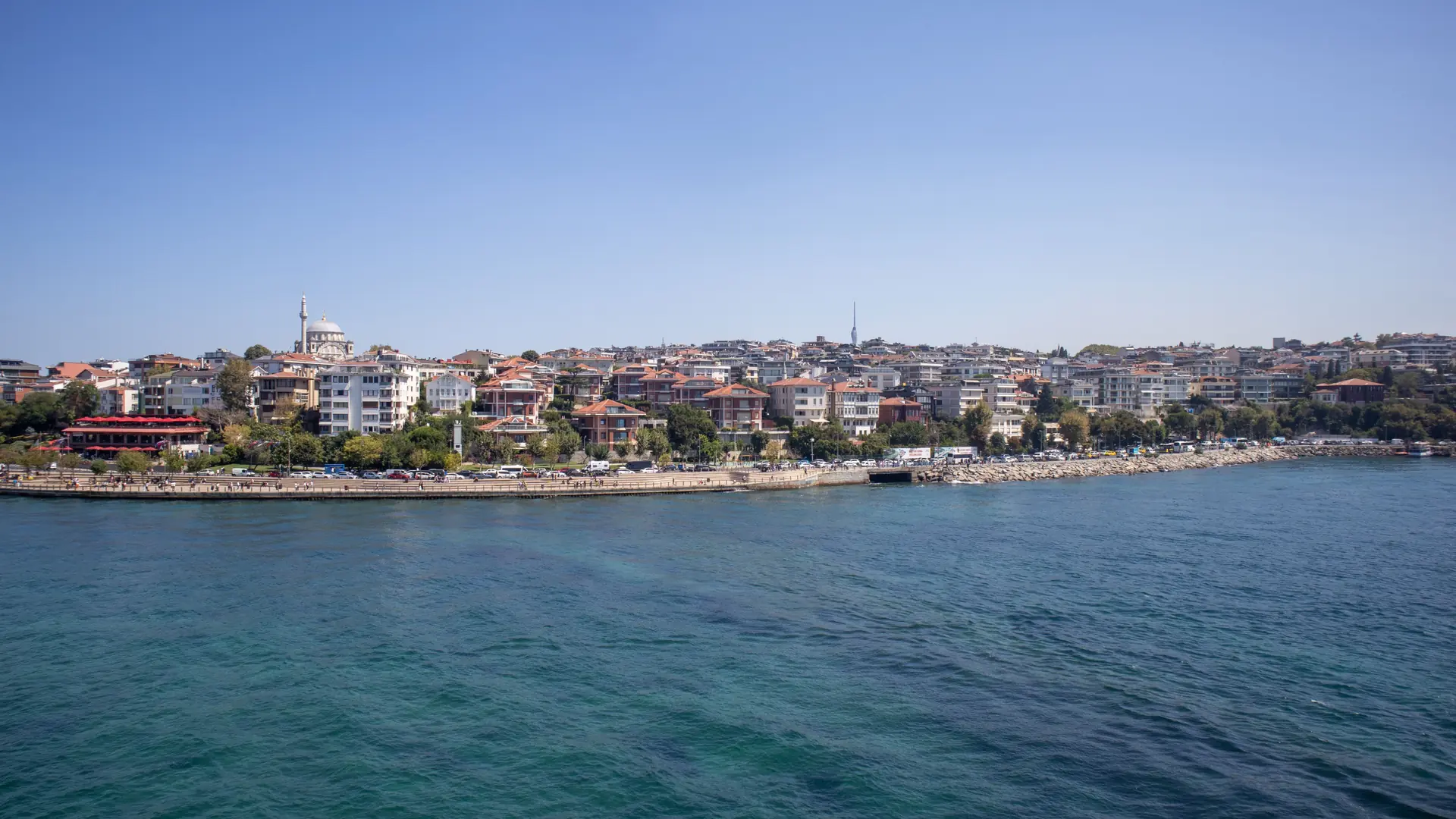Istanbul waterfront buildings and mosque domes across blue water on a sunny day