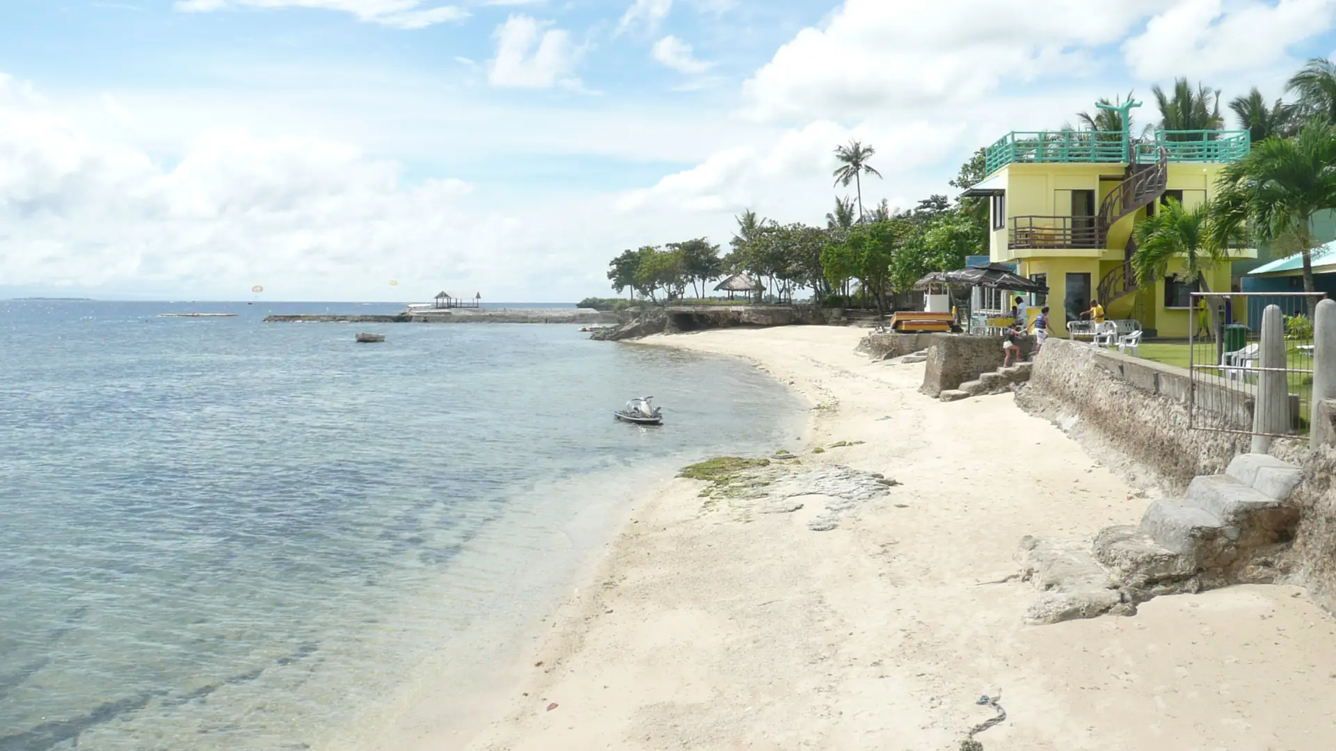 Sandy resort shoreline and palm trees beside clear water on Mactan Island