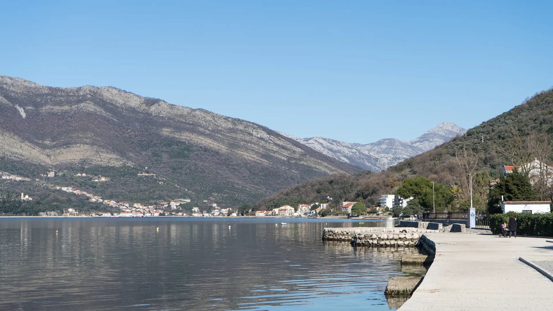Seafront walkway at Donja Lastva, with the bay and mountains beyond