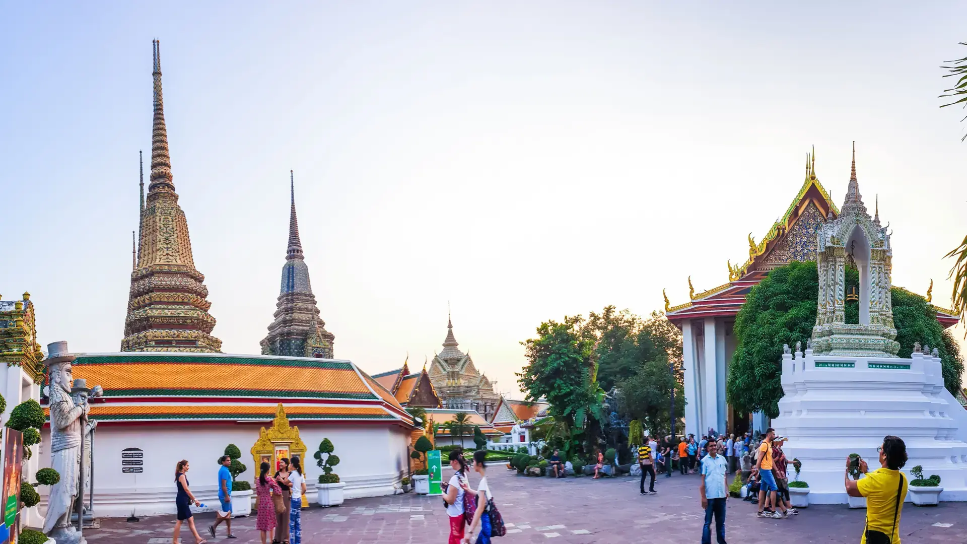 Visitors walking among the gilded roofs and chedis of Wat Pho in Bangkok
