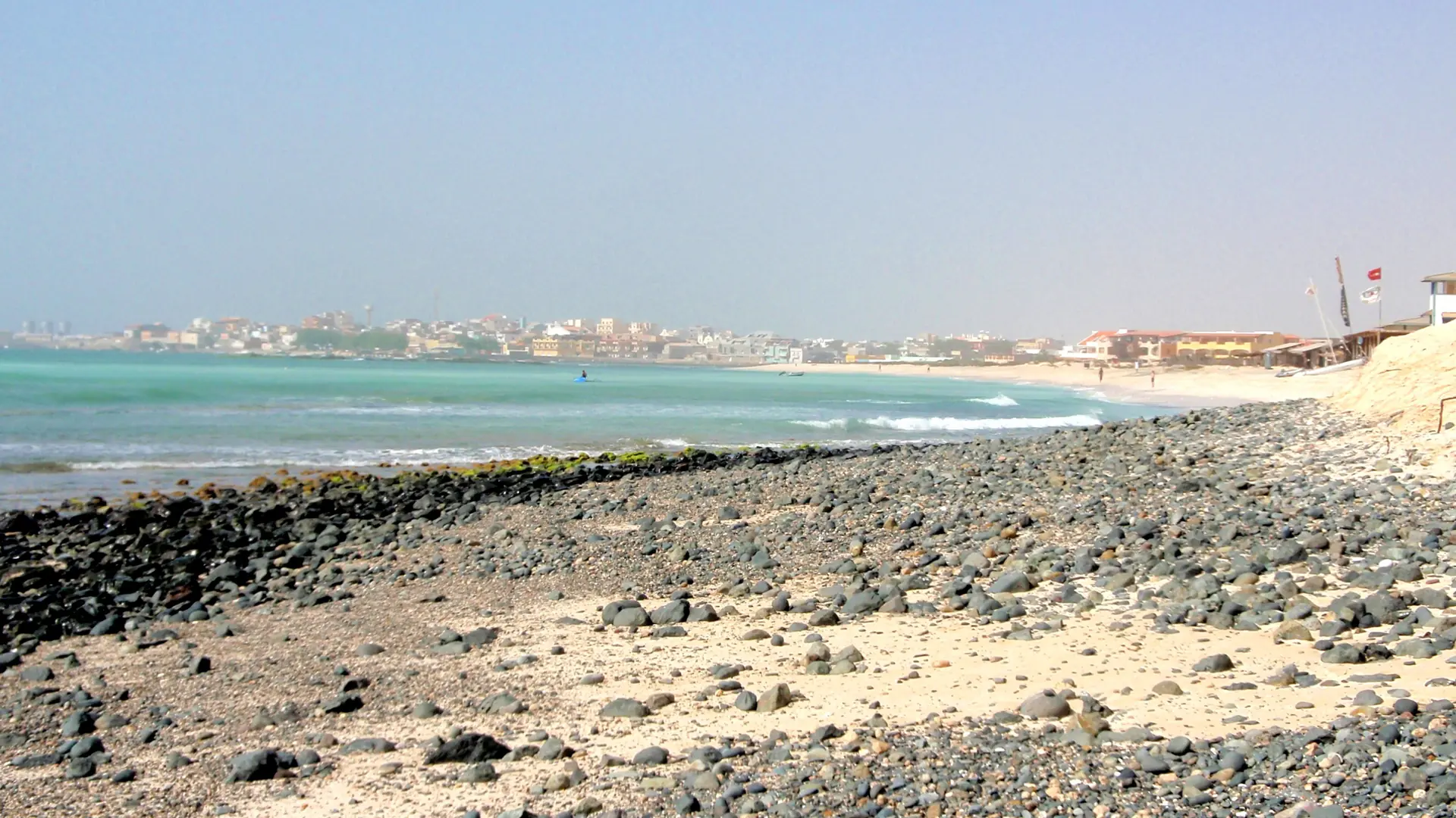 Sunny Sal Rei bay and town seen across Boa Vista’s rocky shore