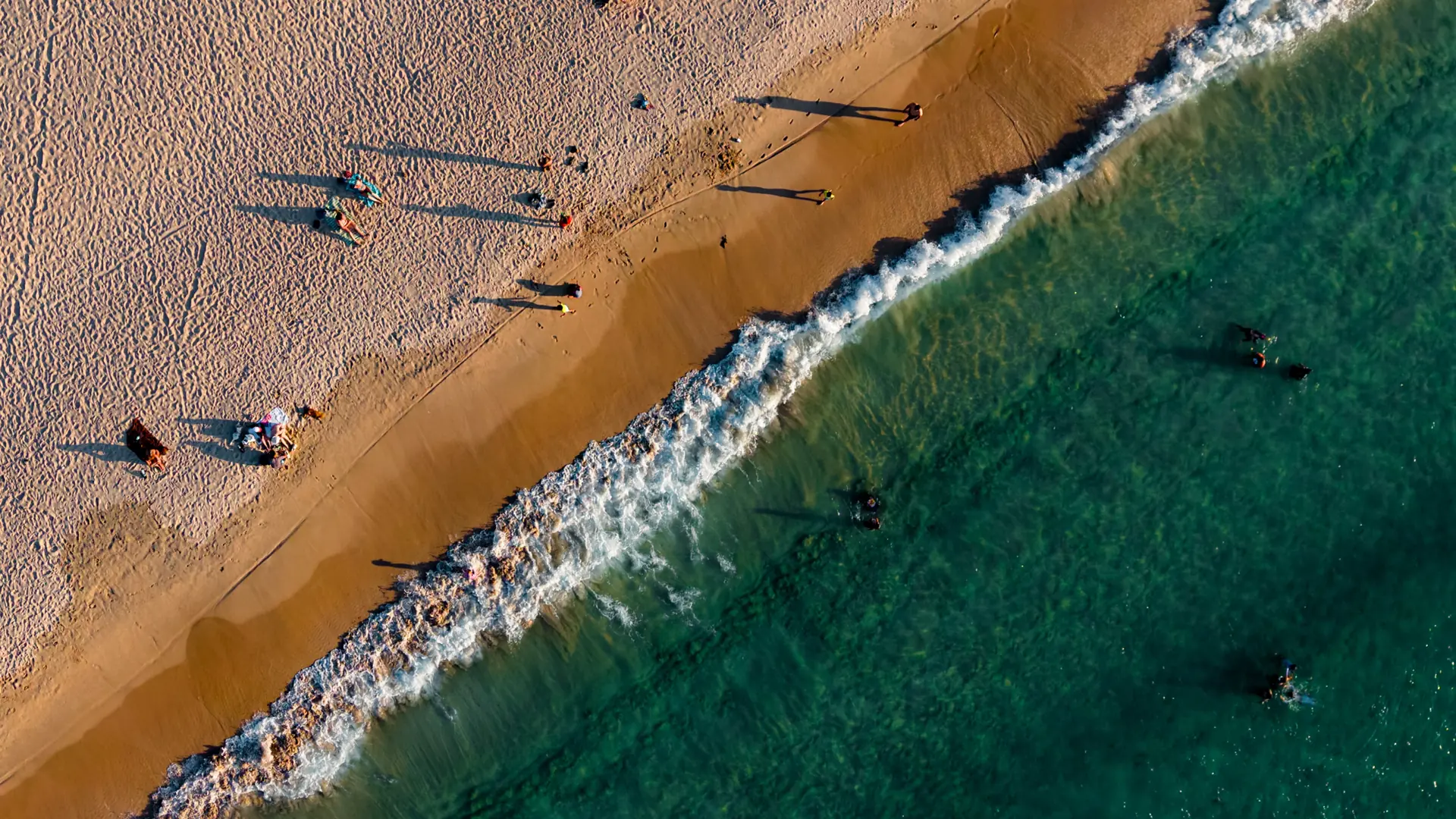 Aerial view of Nacpan Beach, El Nido: golden sand meeting a line of white surf and deep green water