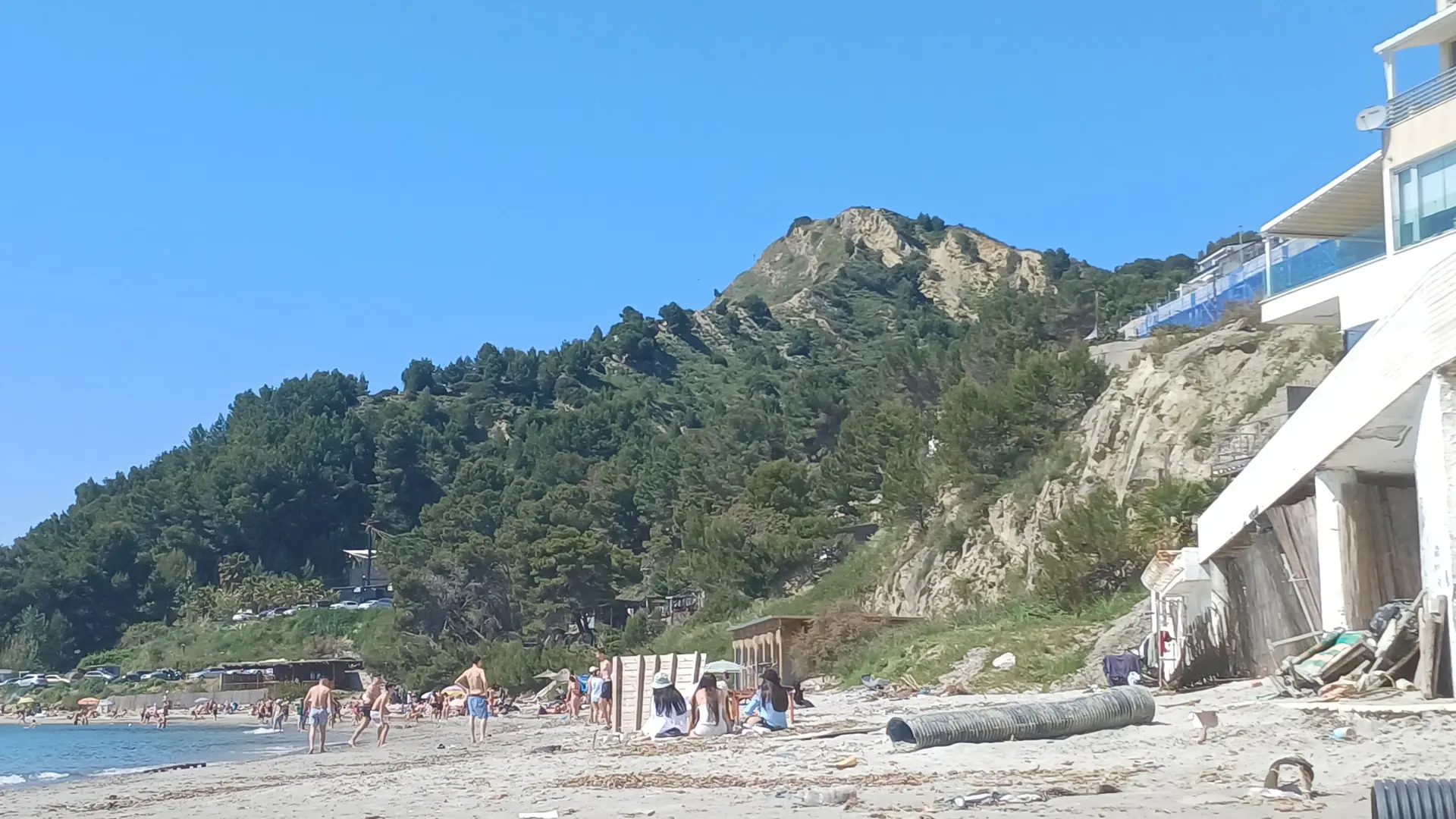 Clear water and a small beach below the green headland at Currila, north of Durrës port