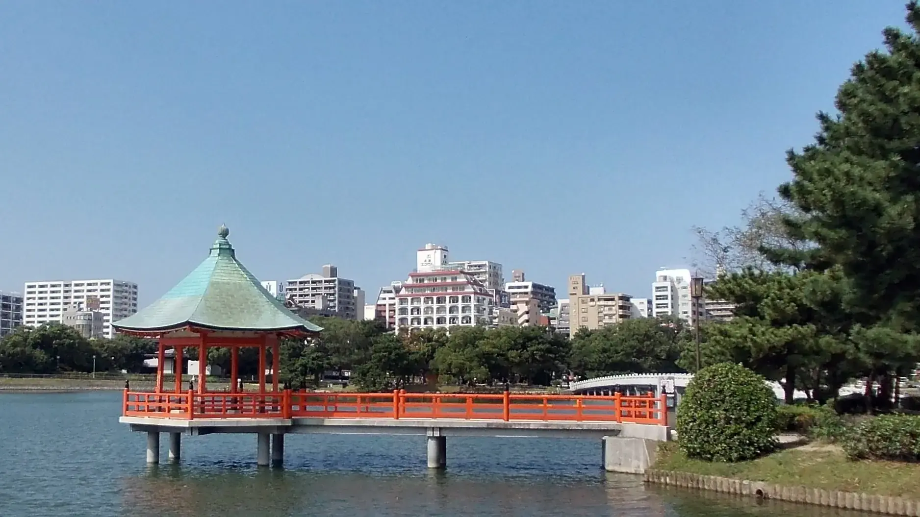 Ohori Park lake, pavilion and vivid green shoreline beneath blue sky