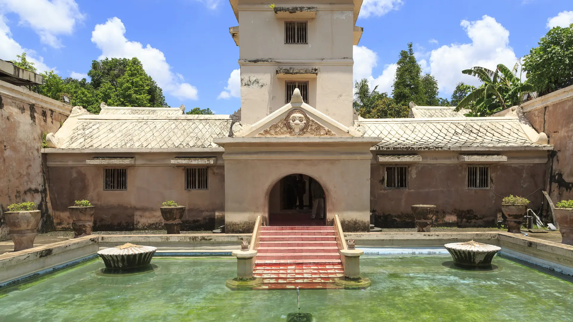 Sunlit bathing pool and carved gateway at Taman Sari in Yogyakarta