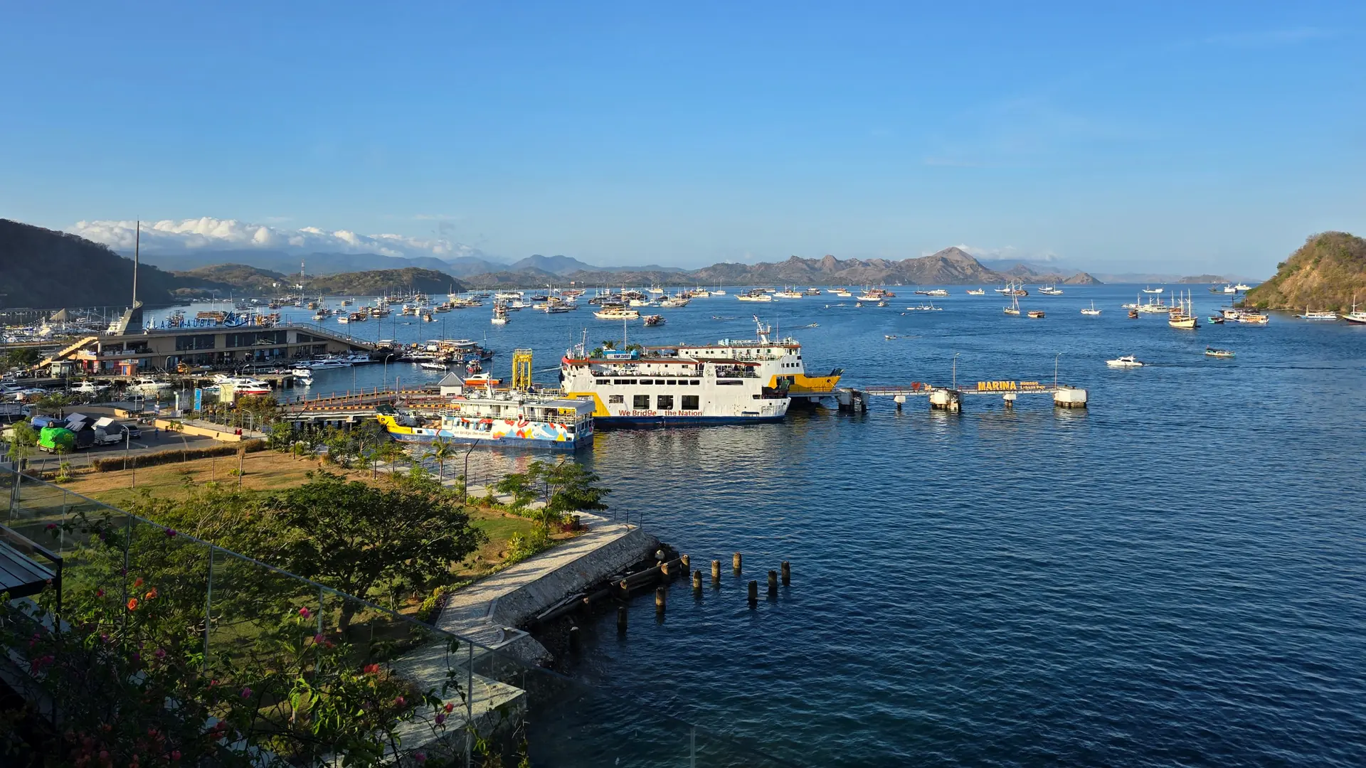 Labuan Bajo’s marina, ferries and anchored boats across a bright blue bay