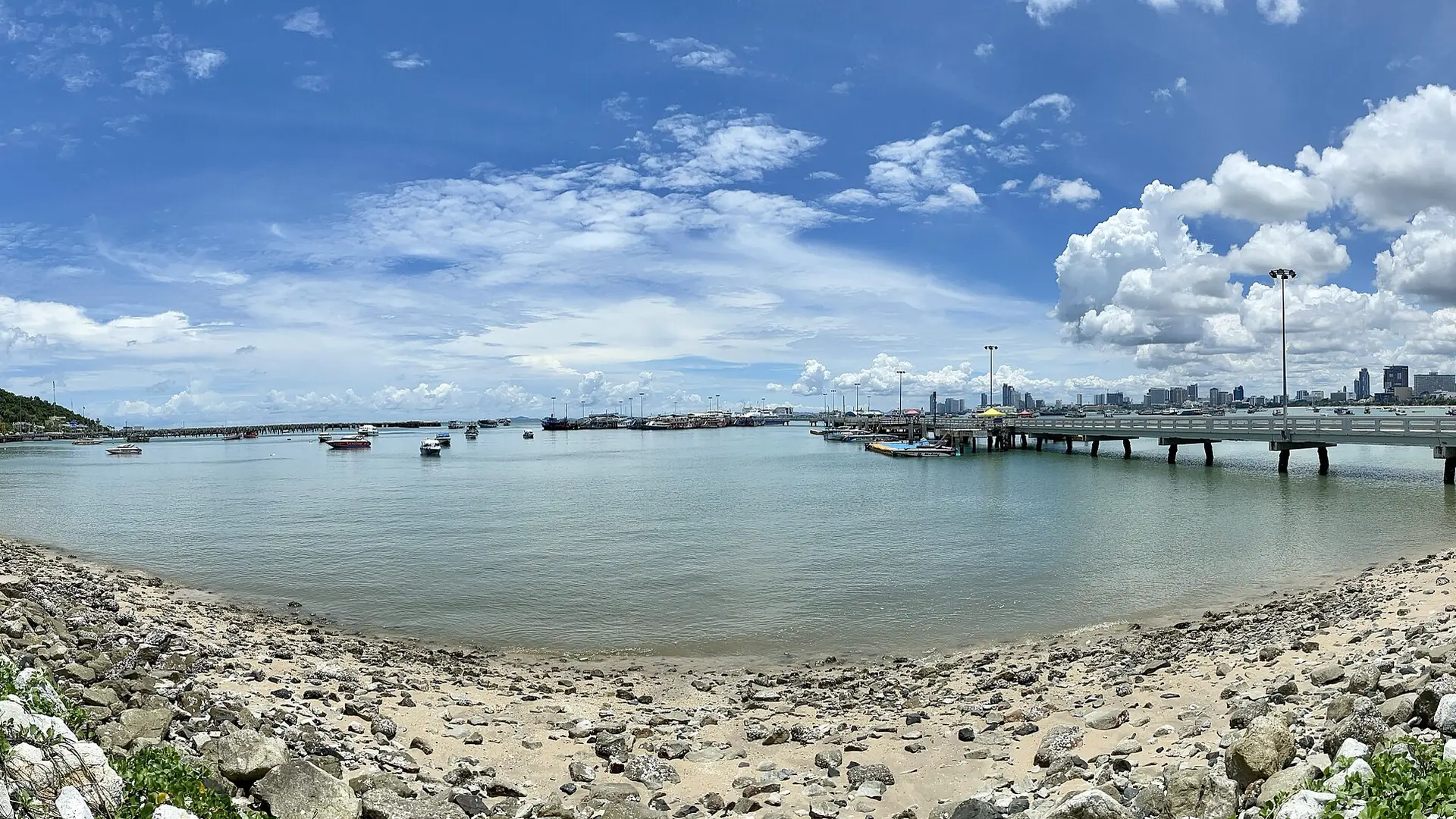 Sunny Pattaya waterfront and pier beside the hillside city sign