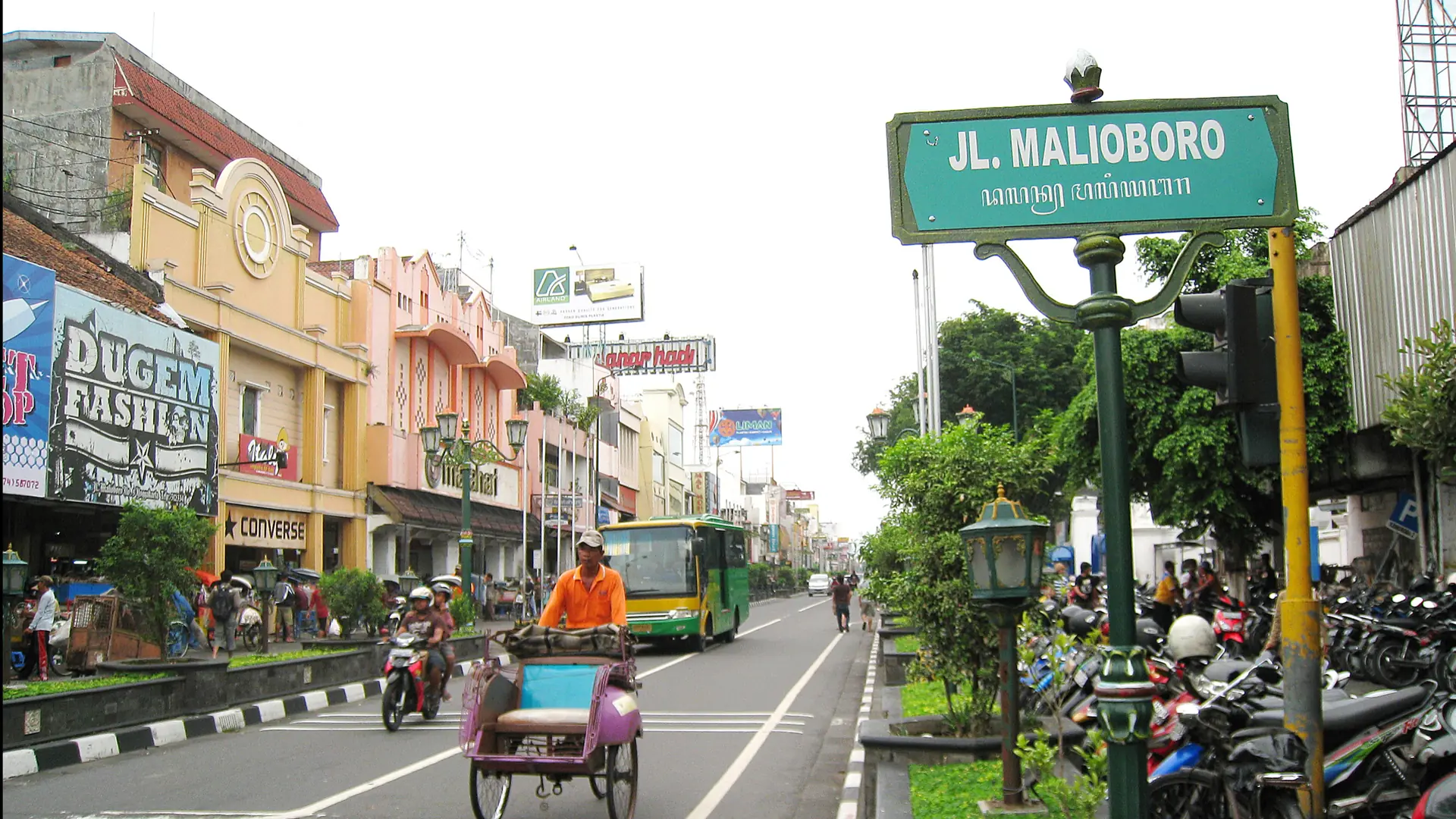 Malioboro’s green street sign, colourful shopfronts and a cycle rickshaw in Yogyakarta