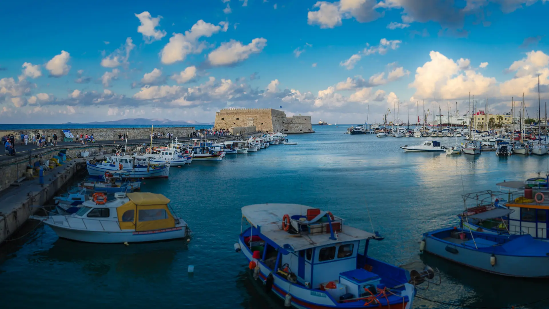 Fishing boats in Heraklion's bright old harbour with Koules Fortress beyond