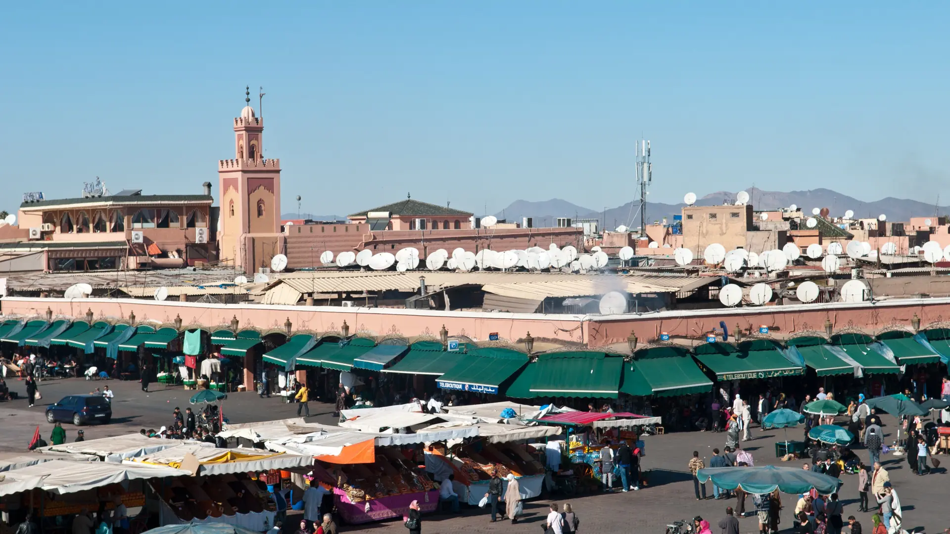 Jemaa el-Fna square filled with daytime market activity beneath a clear sky