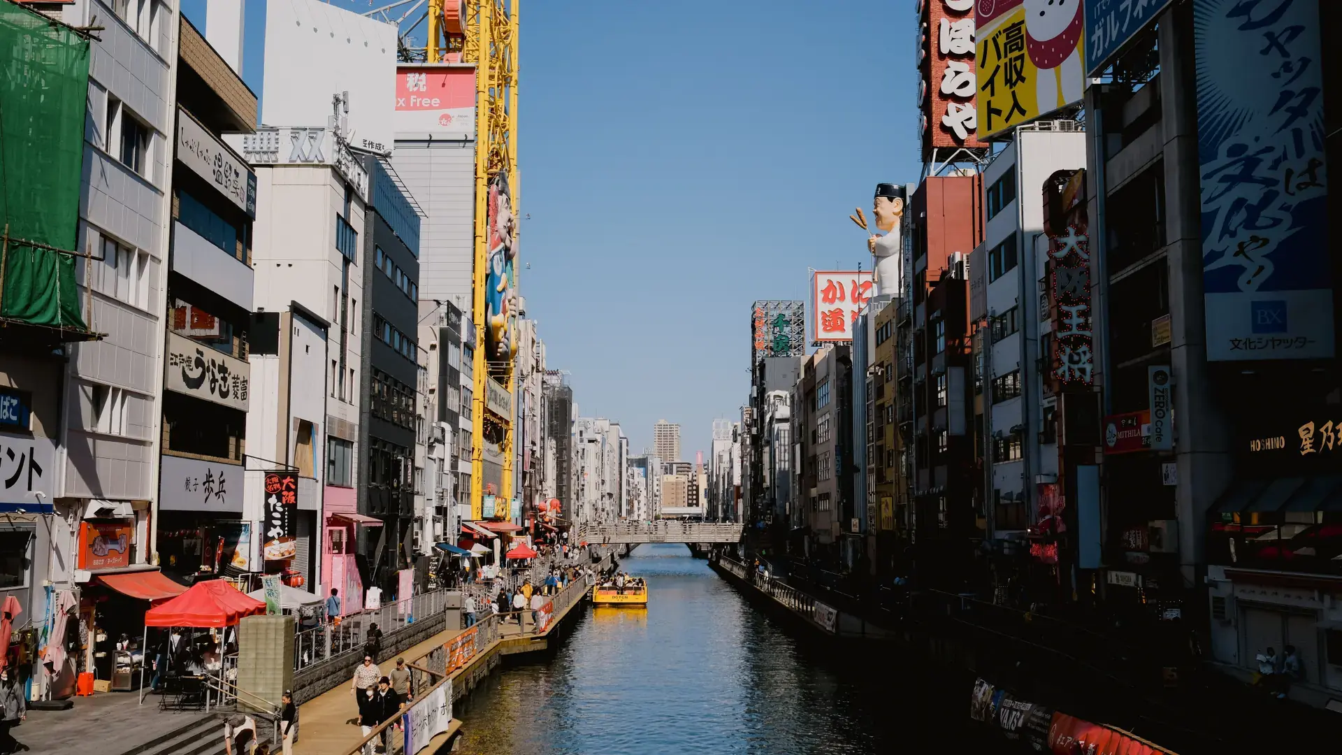vivid blue-sky view over Dotonbori canal and colourful central Osaka signs