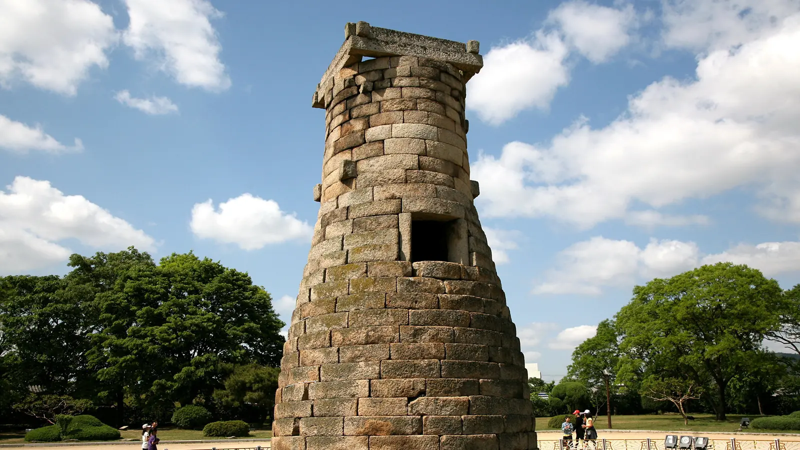 Cheomseongdae Observatory's stone tower in Gyeongju under a bright blue sky with scattered clouds