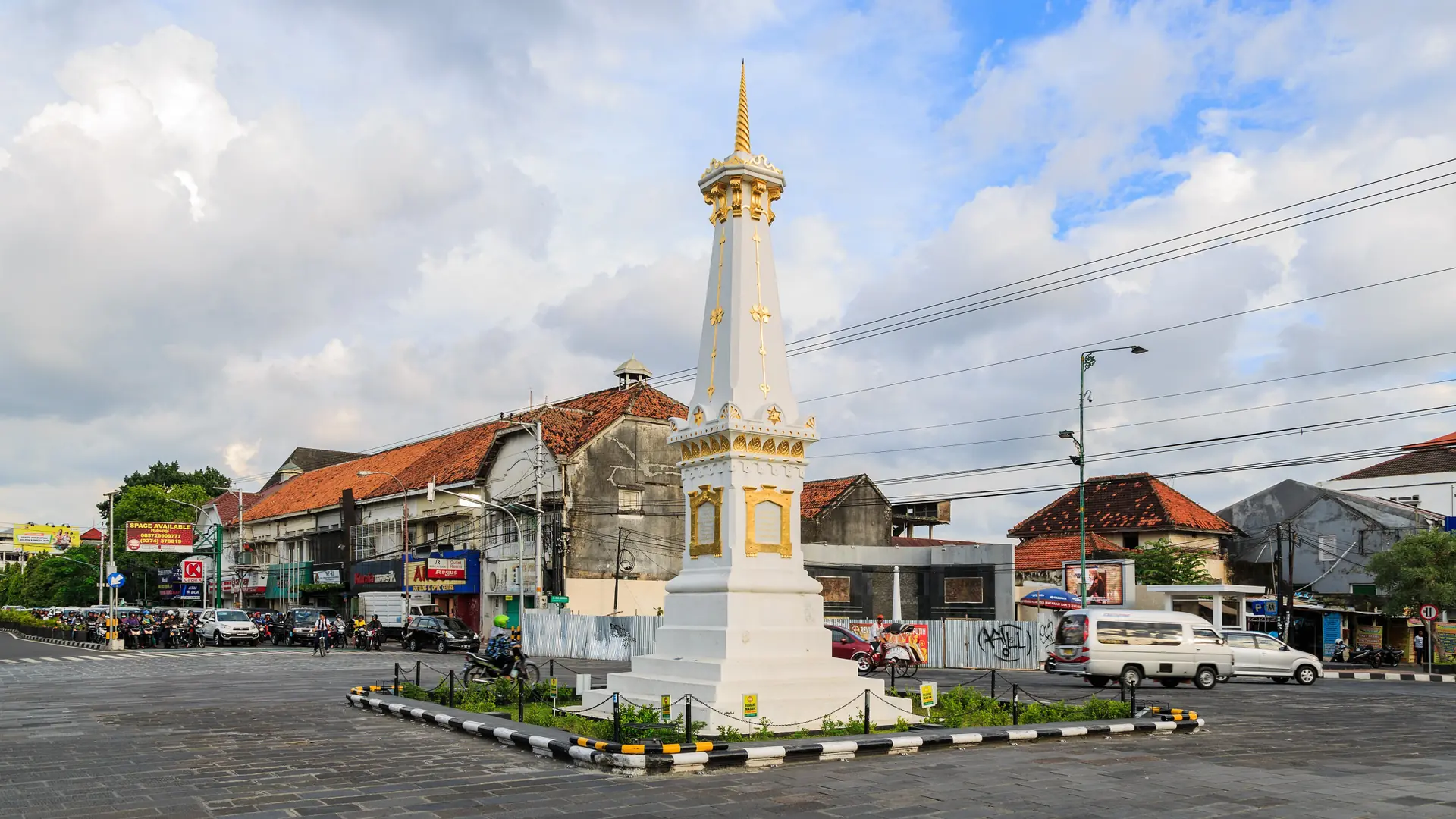 The white and gold Tugu monument above Yogyakarta’s streets in daylight