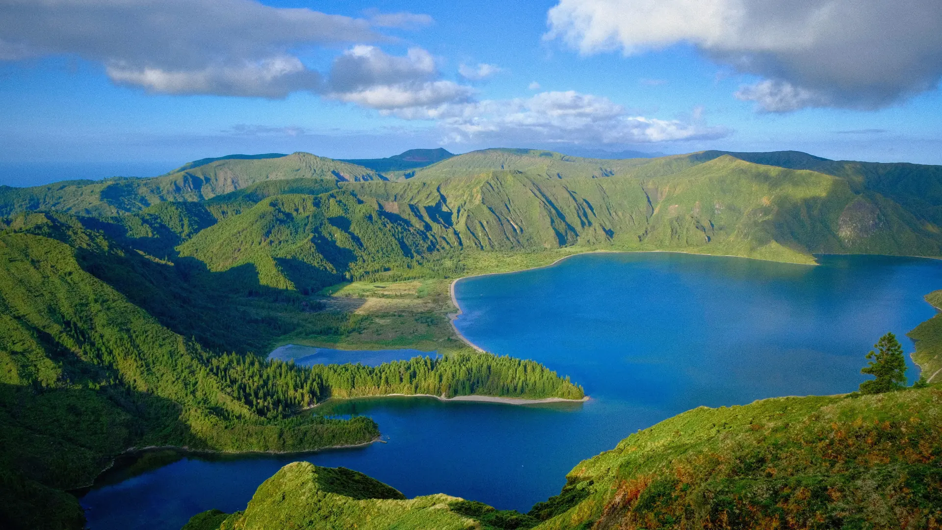 a deep blue crater lake ringed by green volcanic slopes on São Miguel, the Azores