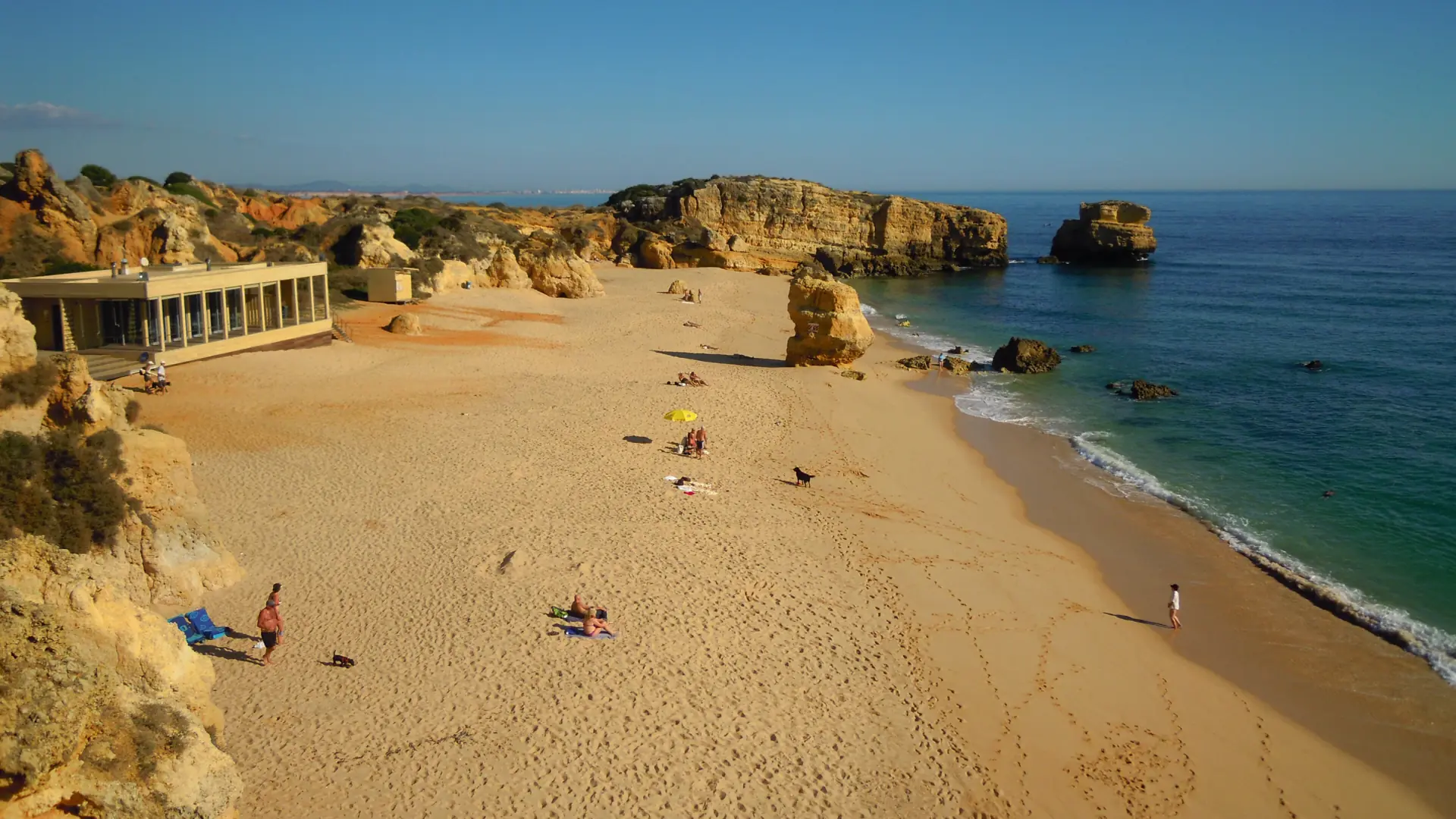 Golden limestone rocks framing the sandy beach at São Rafael in Albufeira