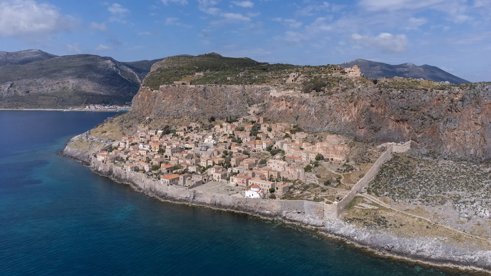 Monemvasia's walled settlement and monumental rock seen from across the blue sea