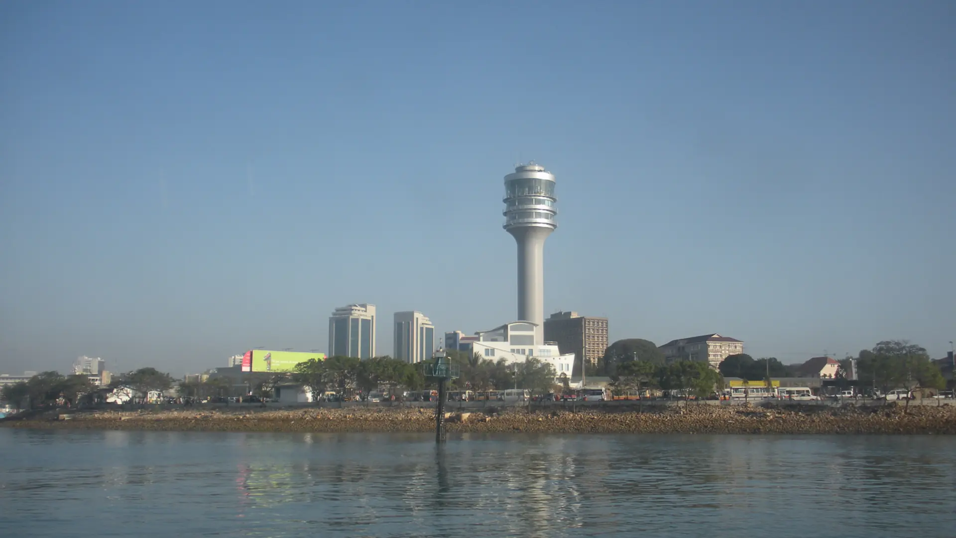 Dar es Salaam waterfront with a tall landmark tower across blue water in daylight