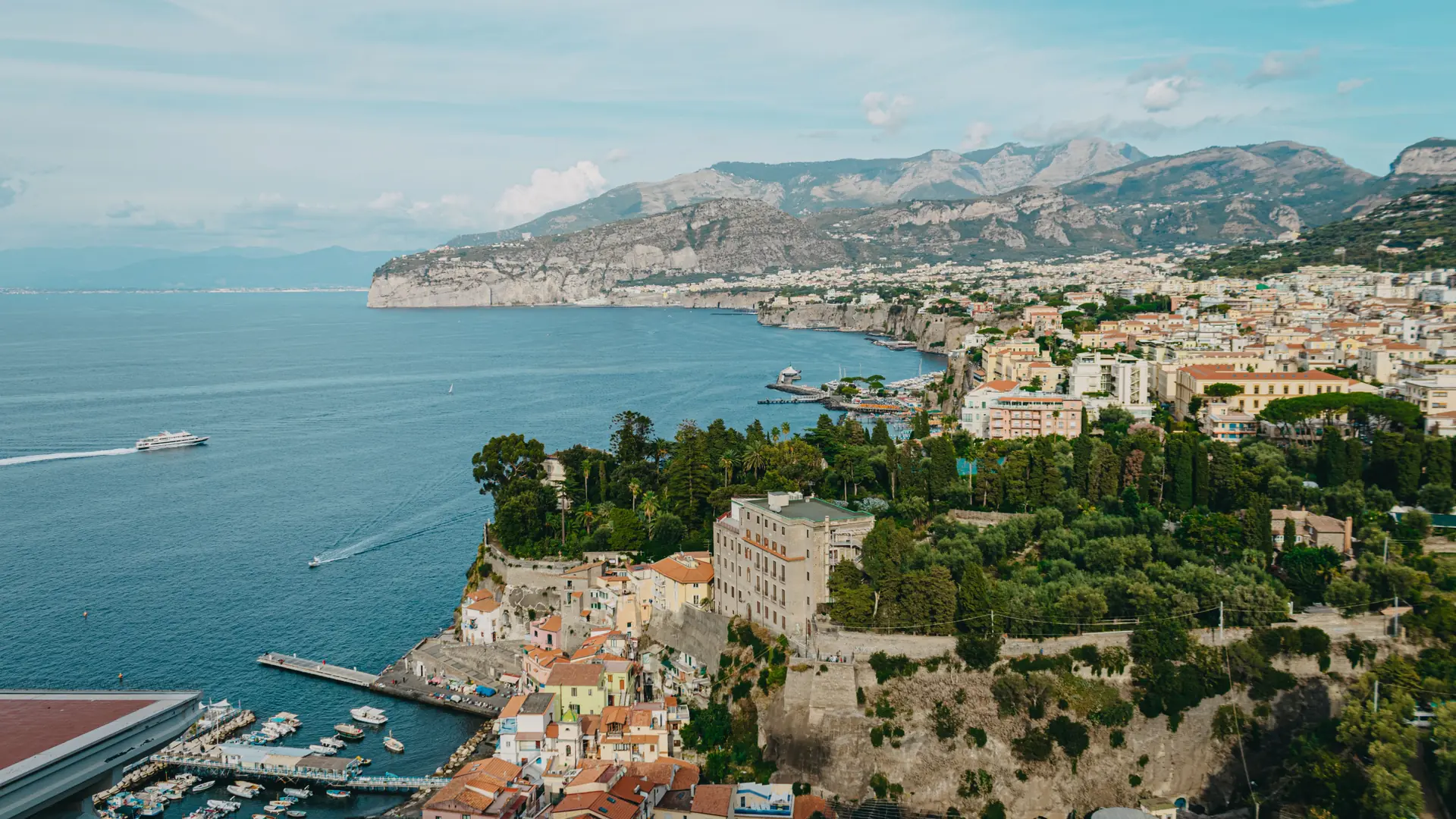 Sorrento’s clifftop buildings and waterfront beside the blue Bay of Naples in daylight.