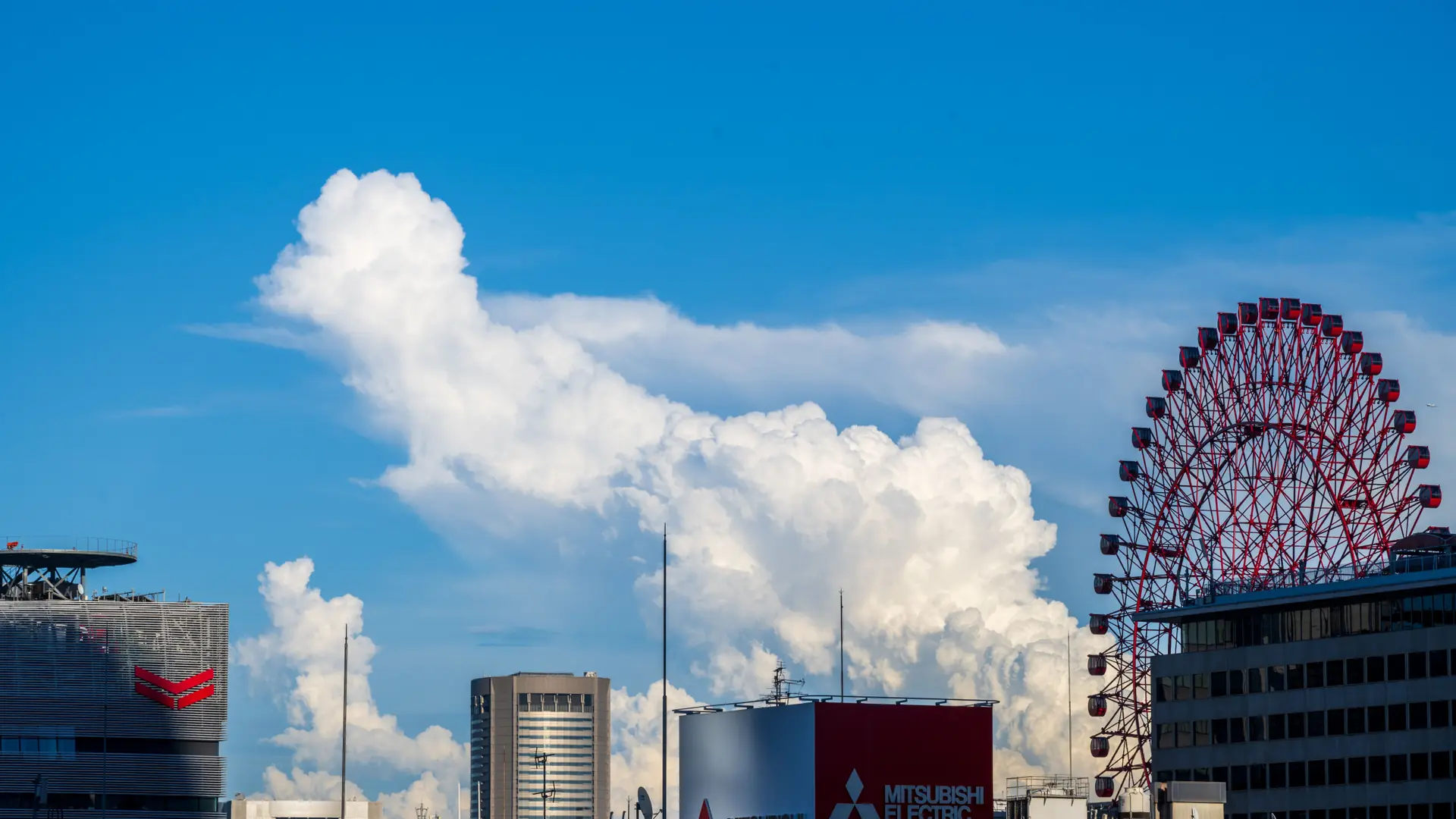 bright Osaka skyline and Ferris wheel beneath a clear blue sky