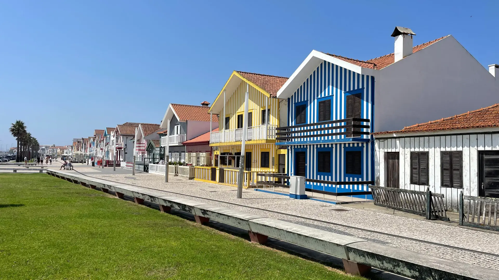 Blue, yellow and white striped palheiros facing the waterside lawns of Costa Nova
