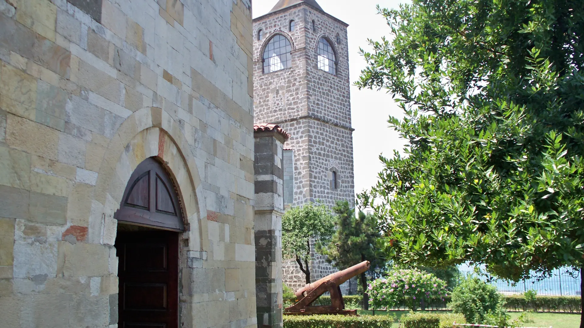 Stone bell tower and garden beside Trabzon’s Hagia Sophia, shown as a wider city scene