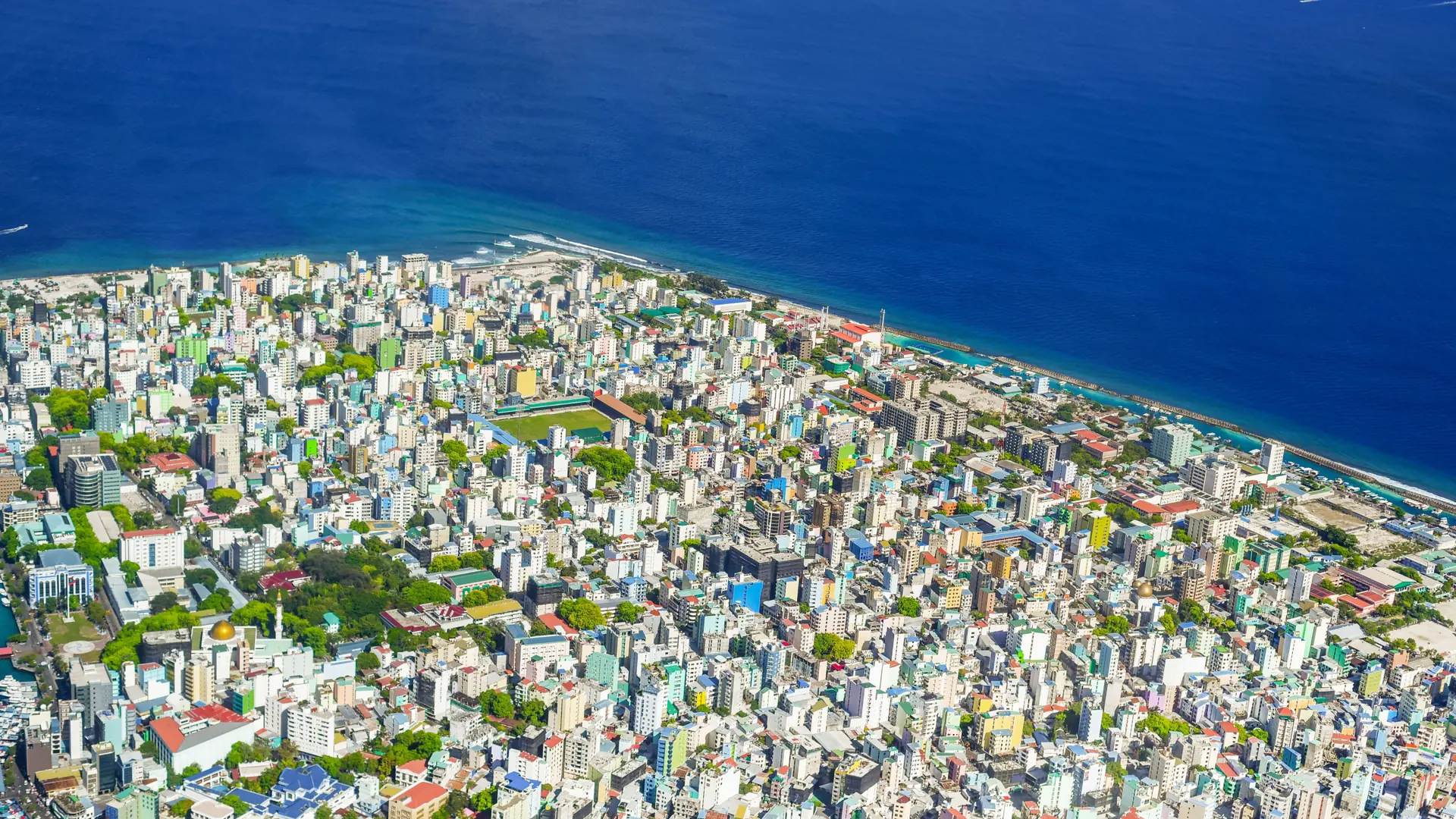 Sunny aerial view across Malé island city and the surrounding blue sea; ward not identified