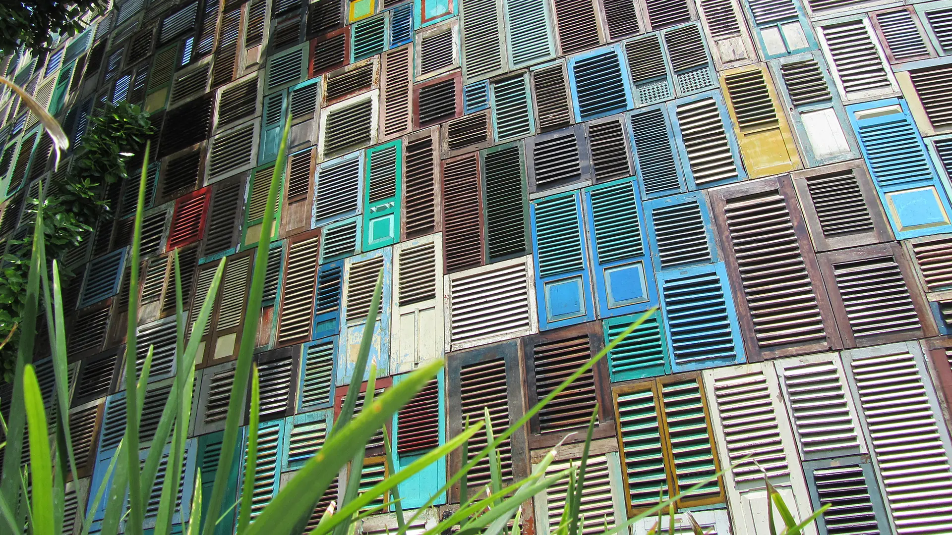 Reused wooden shutters and green plants on Potato Head’s colourful façade in Petitenget