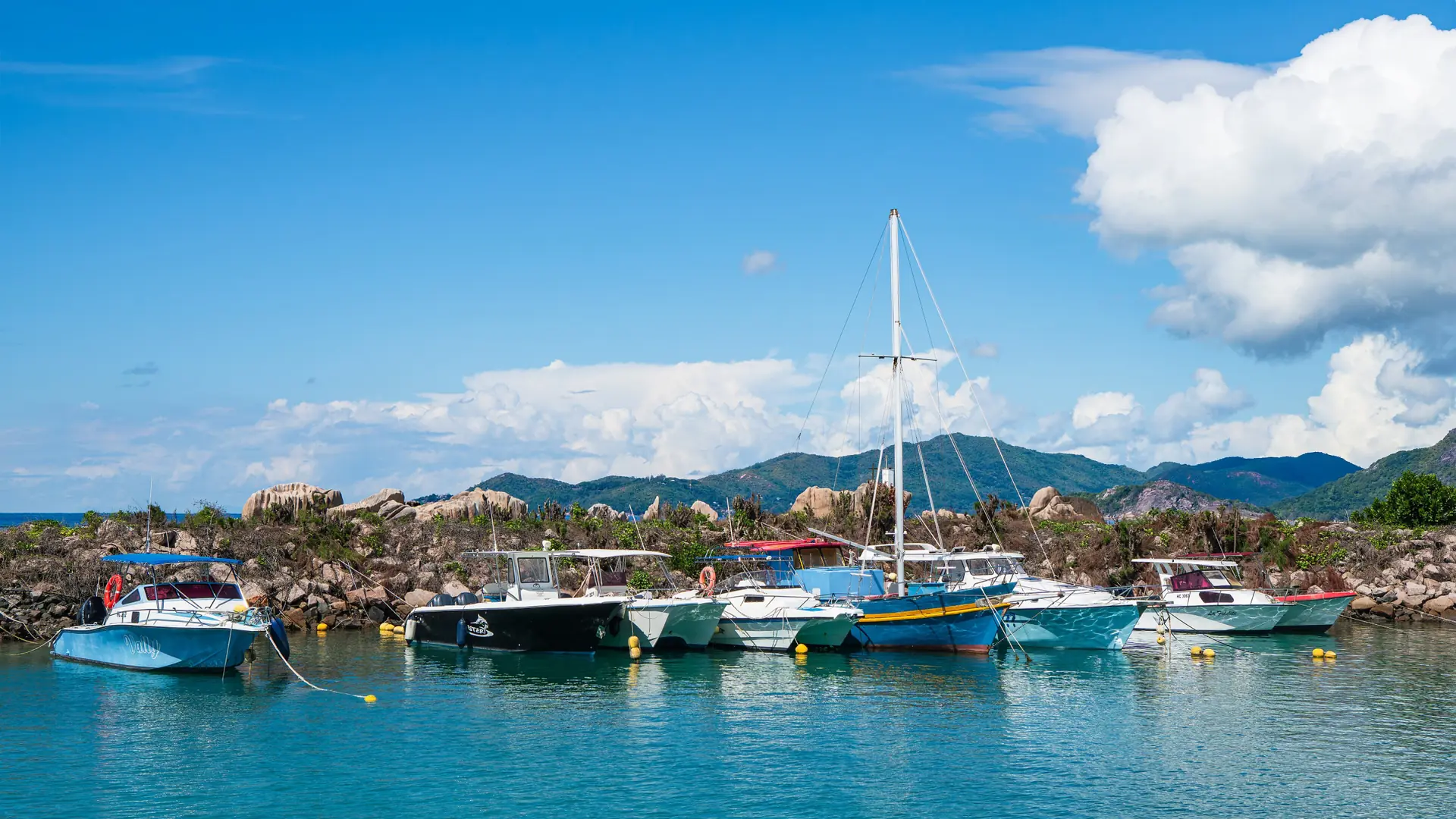 Boats in the sunlit La Digue marina beside La Passe village centre