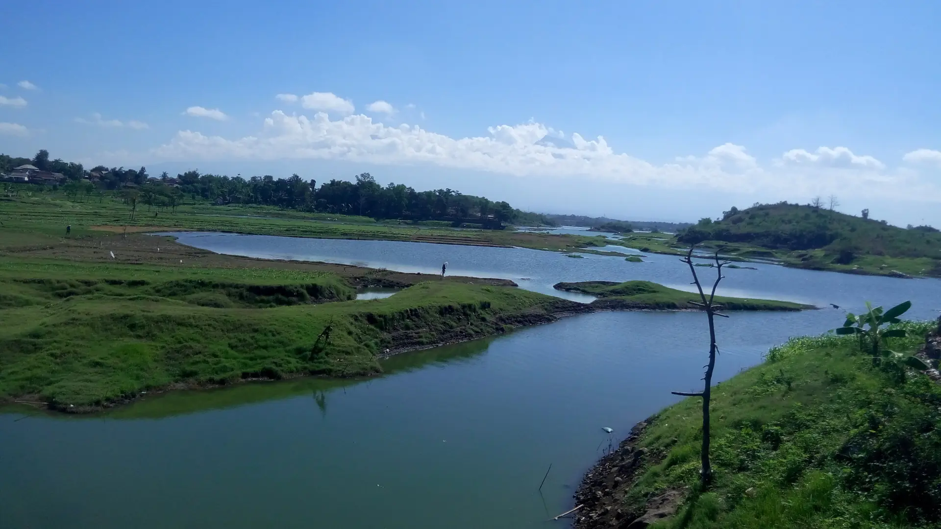 Green fields and the blue water of Pandan Duri reservoir in eastern Lombok