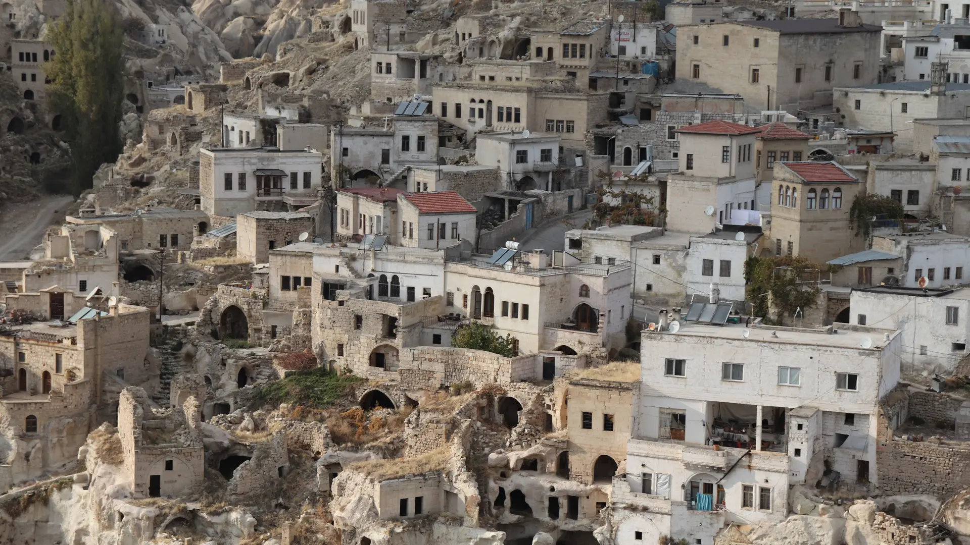 Ancient stone houses built into sunlit rock formations in the Cappadocia region