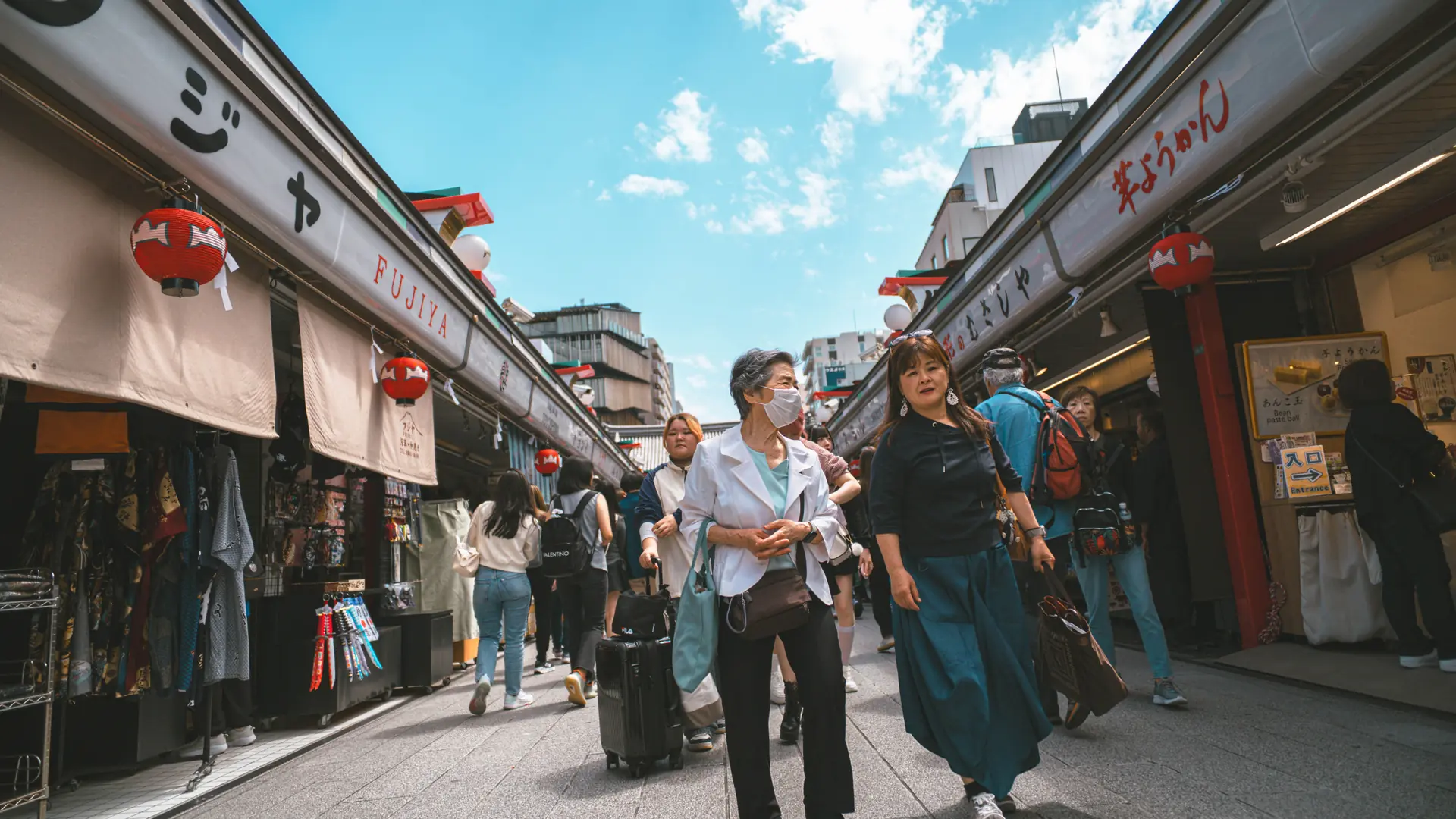 A lively Japanese market lane with colourful food stalls in daylight