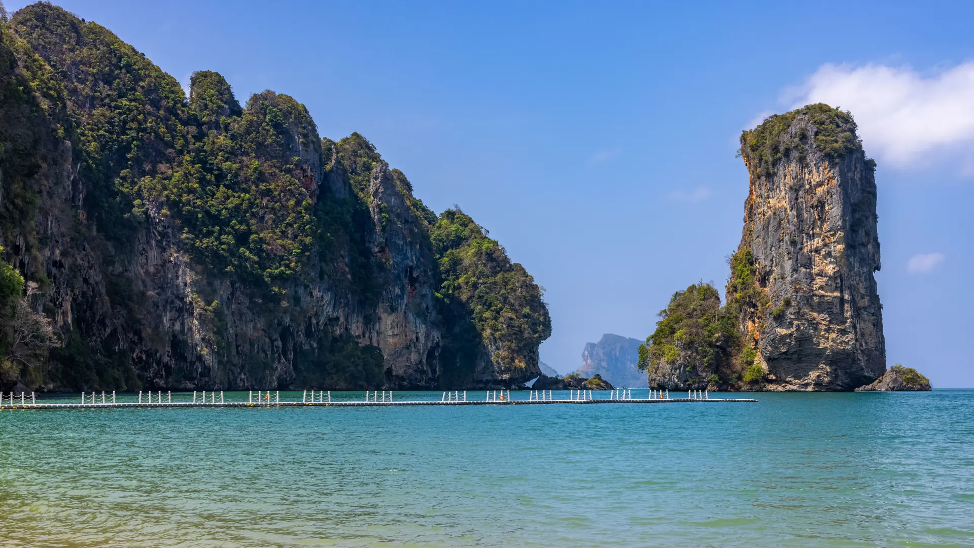 A green limestone islet rising from clear blue water off Krabi