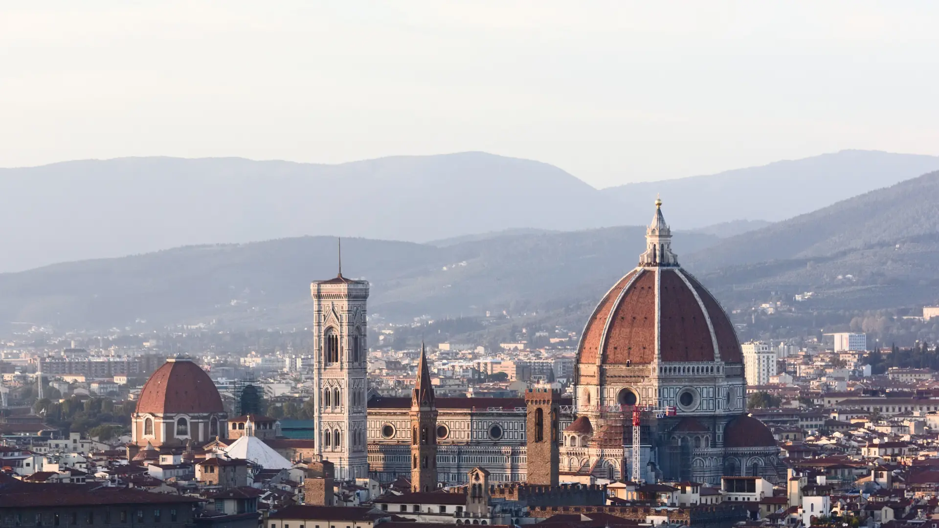 A bright wide view of Florence rooftops with the Duomo rising above the historic centre