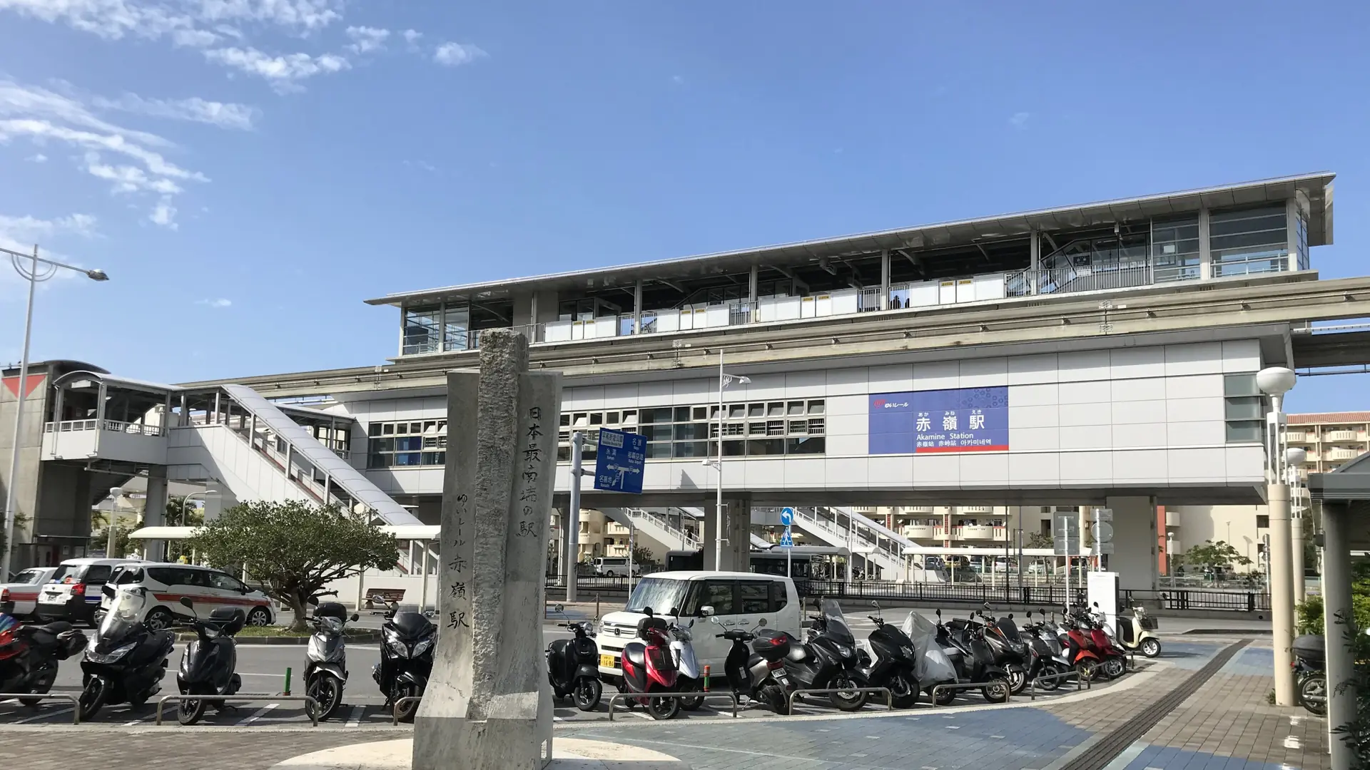Akamine Station and its sunny plaza beside the southernmost-station monument in Naha
