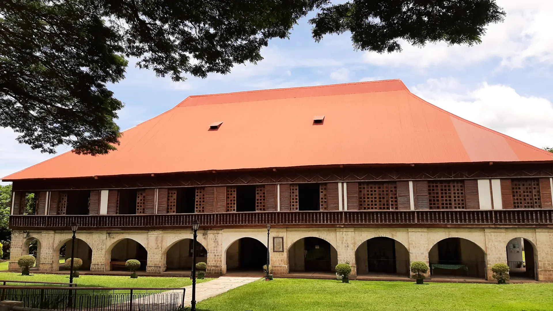 Red roof, wooden upper floor and stone arches of Lazi Convent in daylight