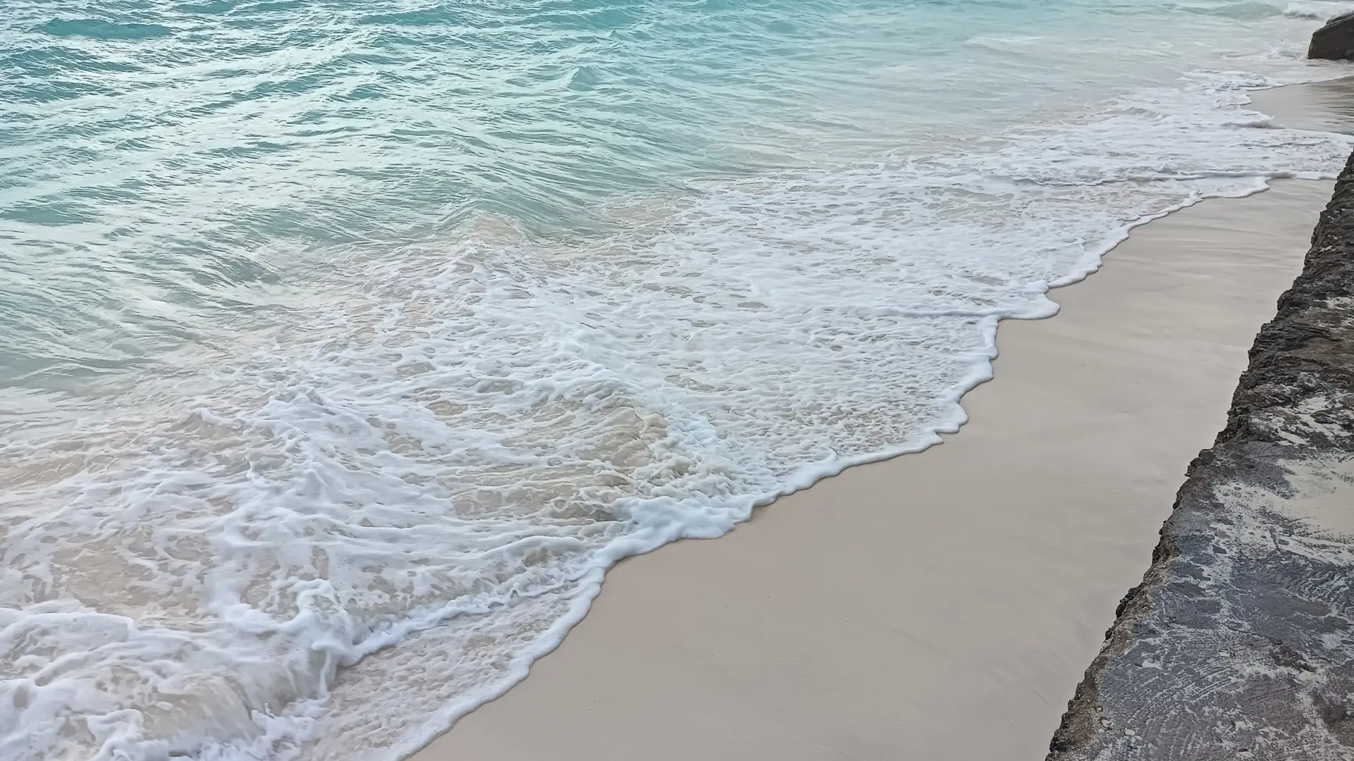 Sunlit pale sand and clear turquoise water along Nungwi Beach