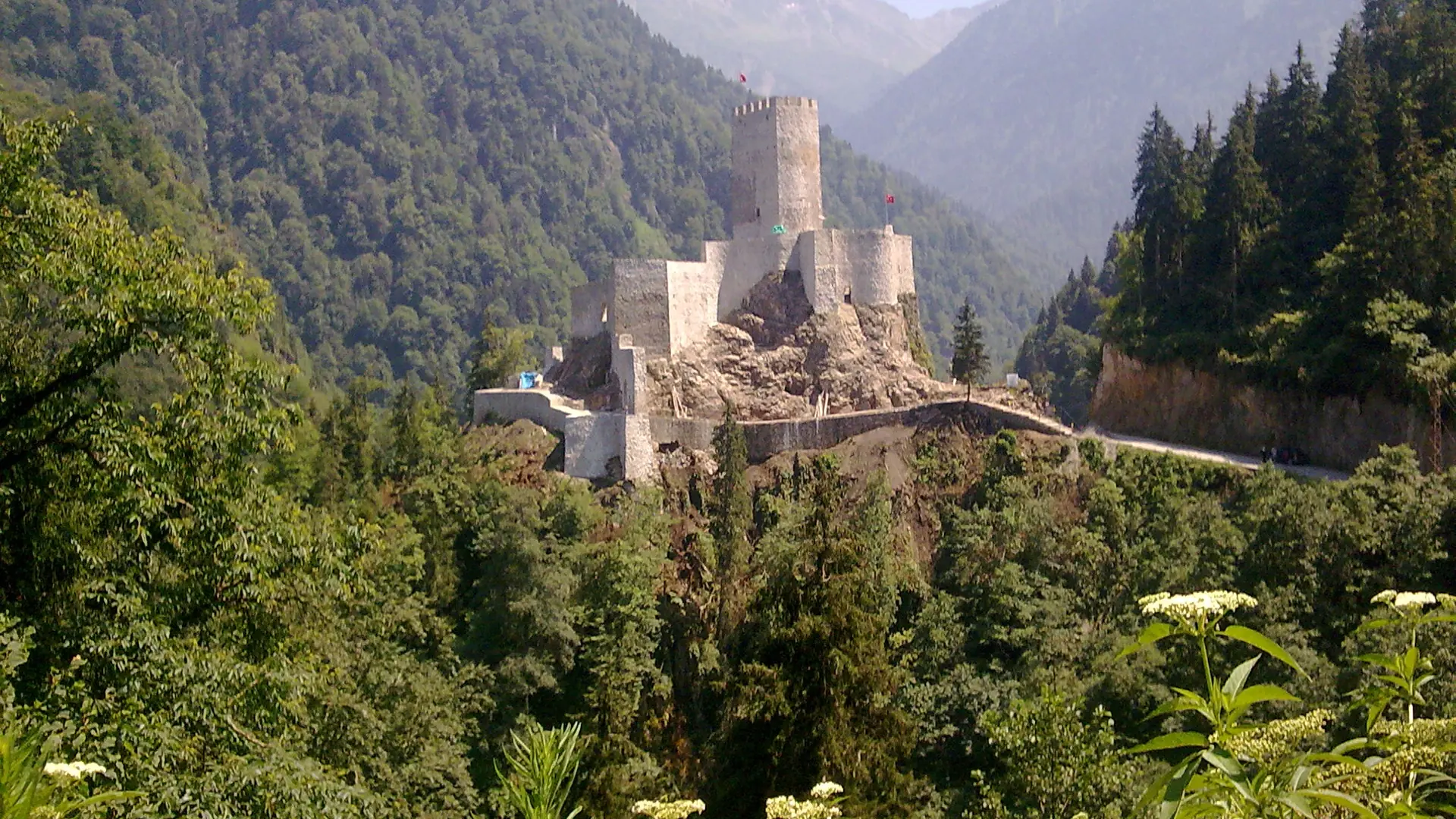 Zilkale’s tall keep and stone enclosures standing above a forested Fırtına valley in daylight