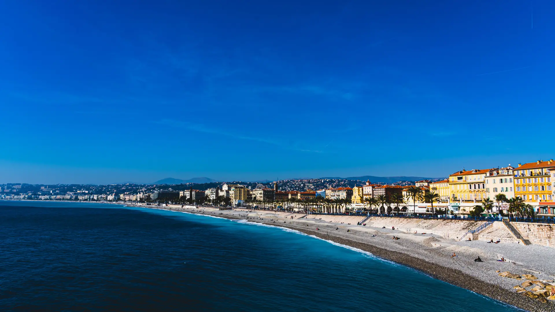 Nice’s curved pebble beach and Promenade des Anglais beside the blue Baie des Anges