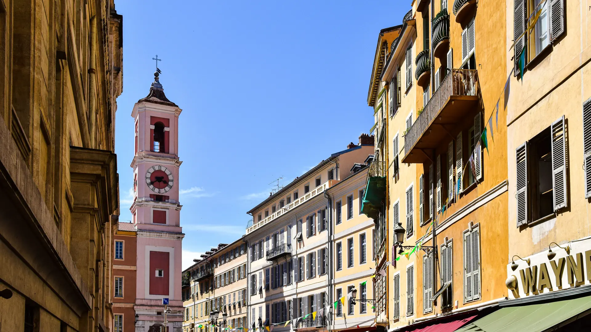 Sunlit façades and a pink bell tower in Old Nice