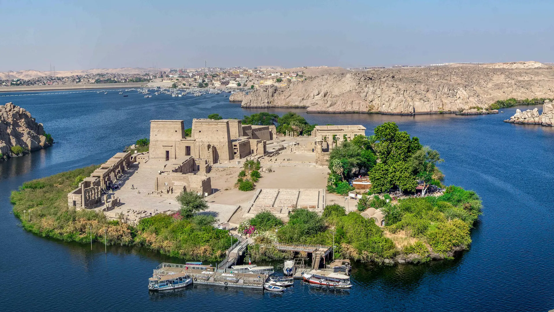Bright aerial view of Philae temple island set in blue Nile water near Aswan.
