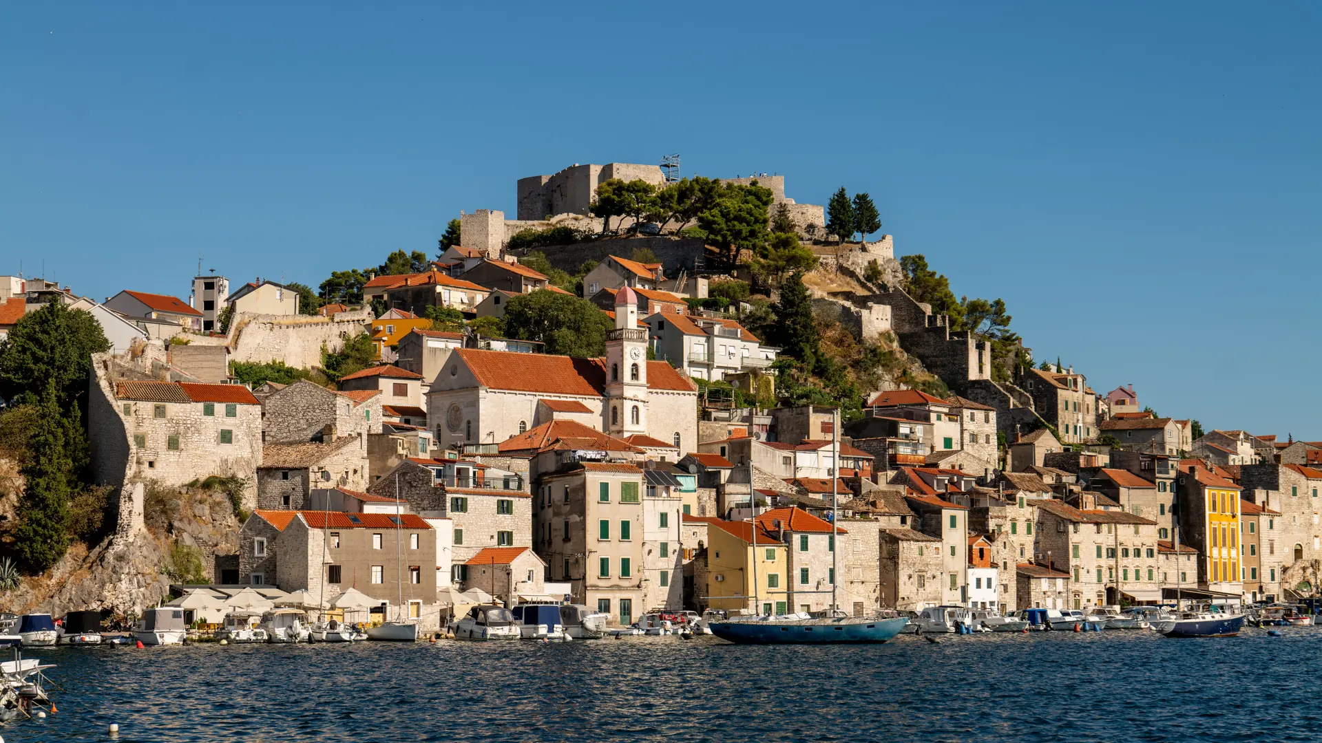 Šibenik’s pale stone old town and cathedral rising above the blue harbour in clear daylight